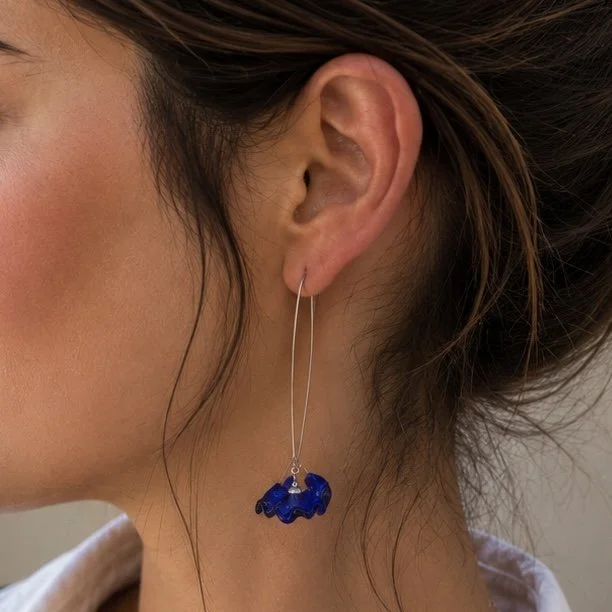 Mujer llevando pendientes Onde Azul de vidrio de Murano artesanal y plata de ley con reflejos azules luminosos.