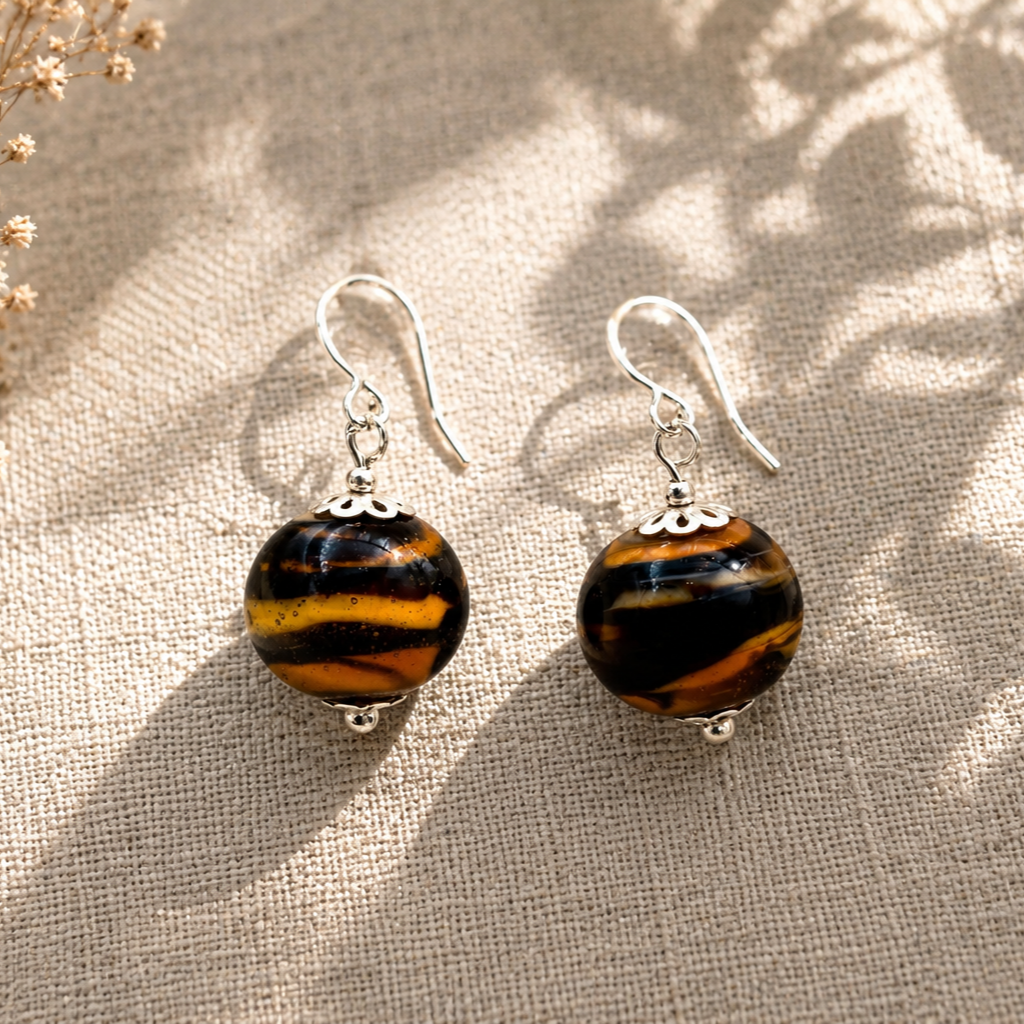 Pendientes Ayla de vidrio de Murano artesanal y plata de ley en suaves tonos anaranjados con delicados detalles decorativos.