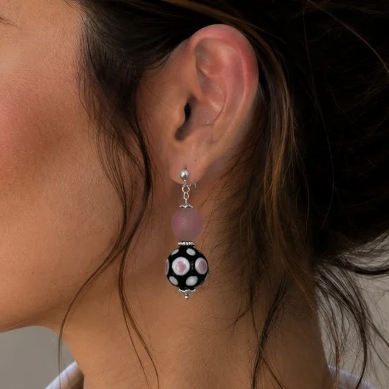 Mujer llevando pendientes Real Rosa de vidrio de Murano artesanal y plata de ley con reflejos suaves y femeninos.