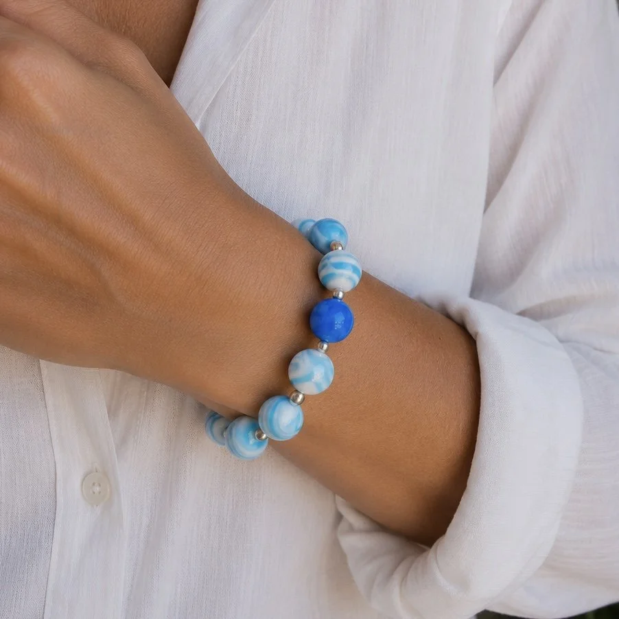 Mujer llevando pulsera Mar de vidrio de Murano artesanal y plata de ley con luminosos tonos marinos.