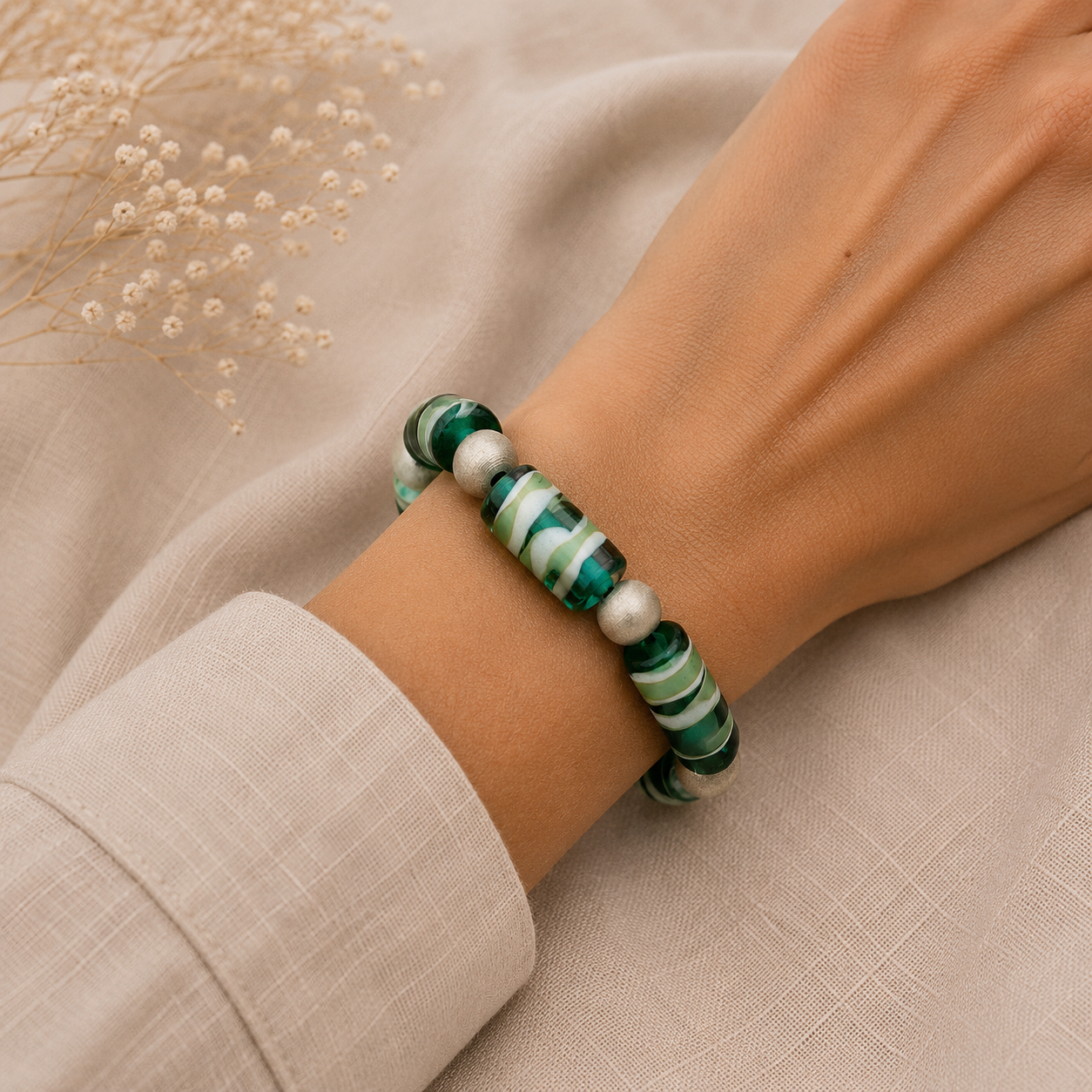 Mujer llevando pulsera Aqua de vidrio de Murano artesanal y plata de ley con luminosos tonos acuáticos.