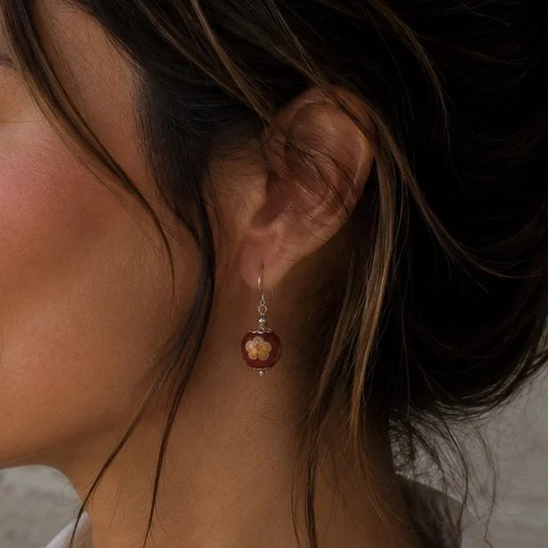 Mujer llevando pendientes Bloom Naranja de vidrio de Murano artesanal y plata de ley inspirados en el atardecer y las flores.