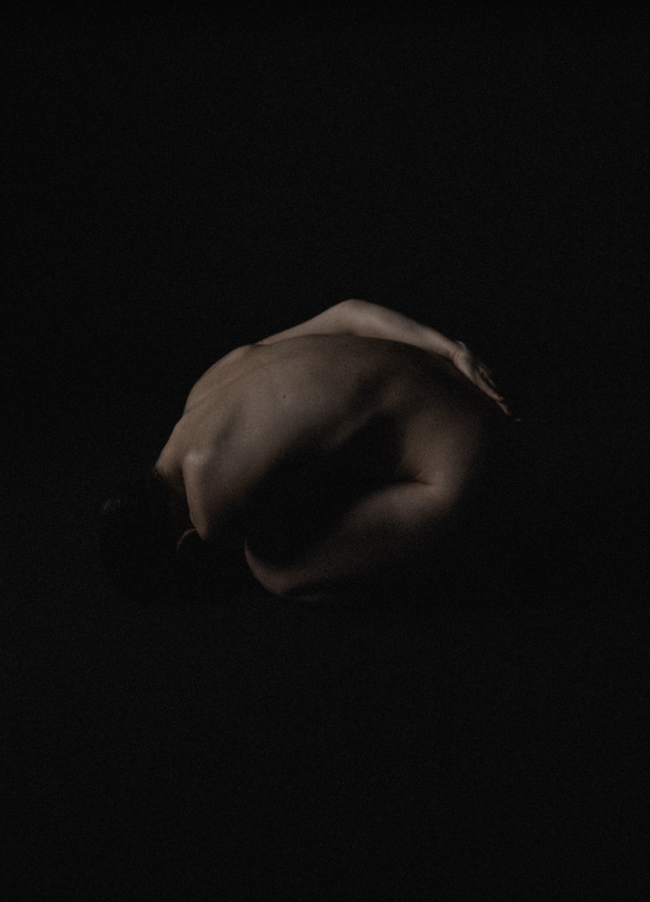 A human hand resting on a dark surface with shadows creating a moody, artistic effect.
