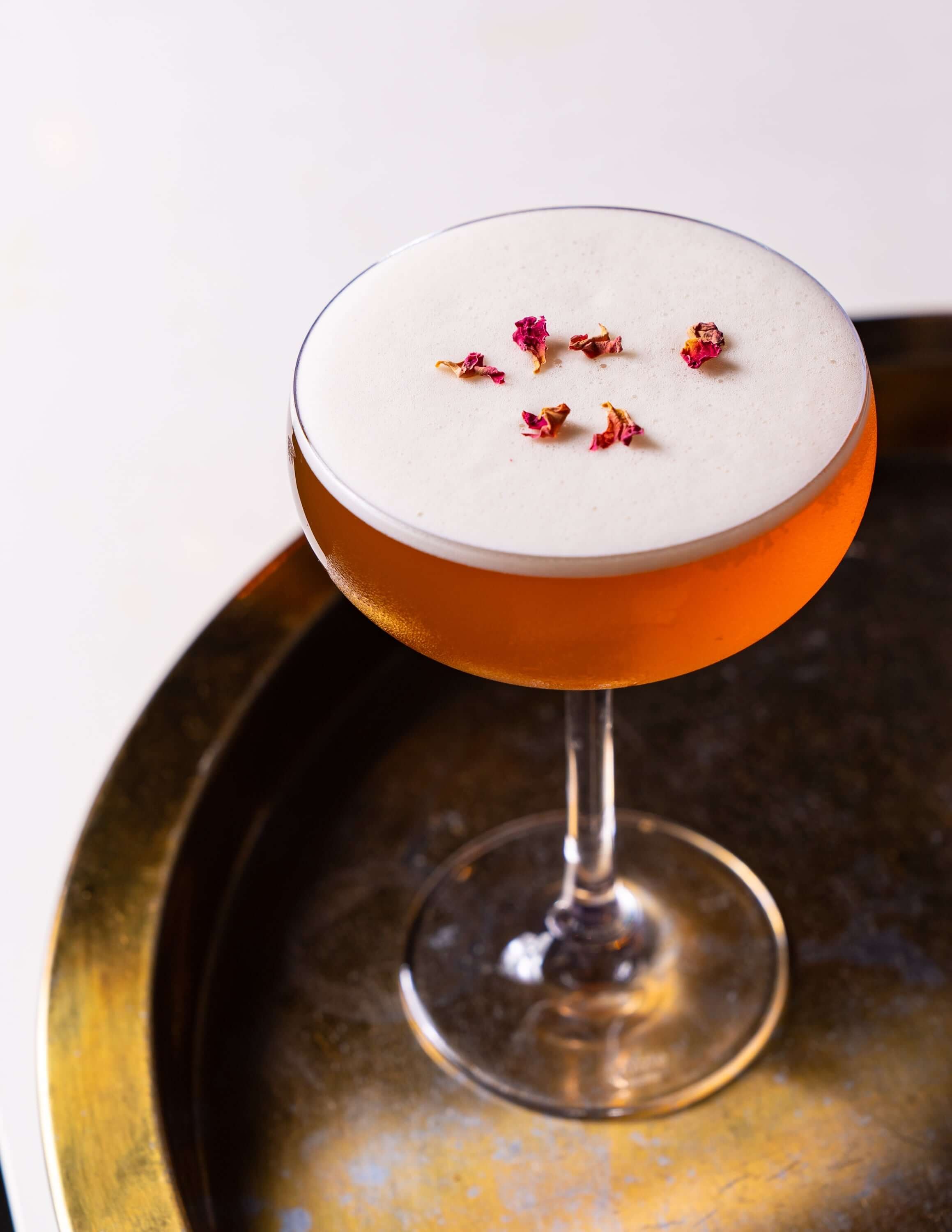  a beautiful blush pink cocktail on a brass tray 