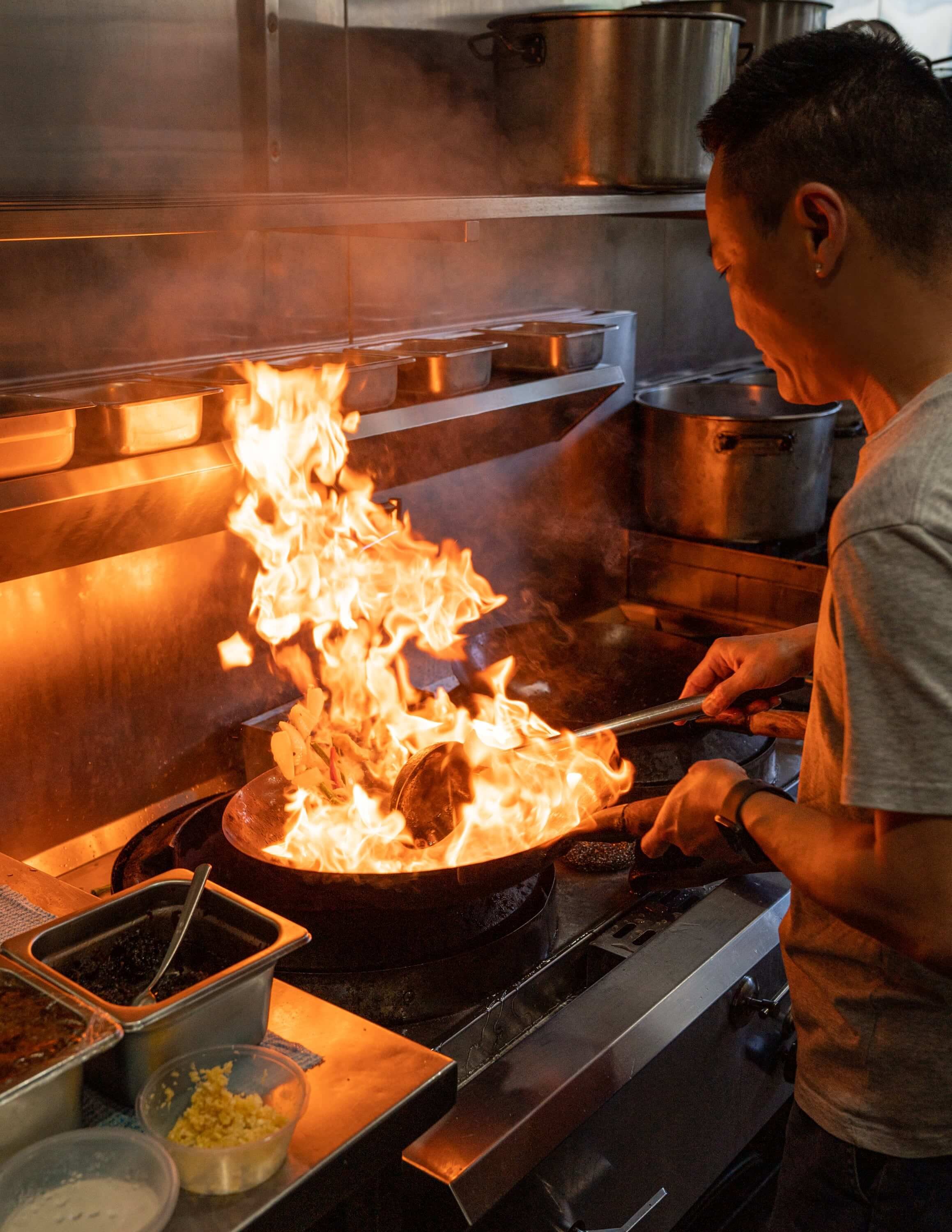  A chef cooking in a wok with dramatic flames  