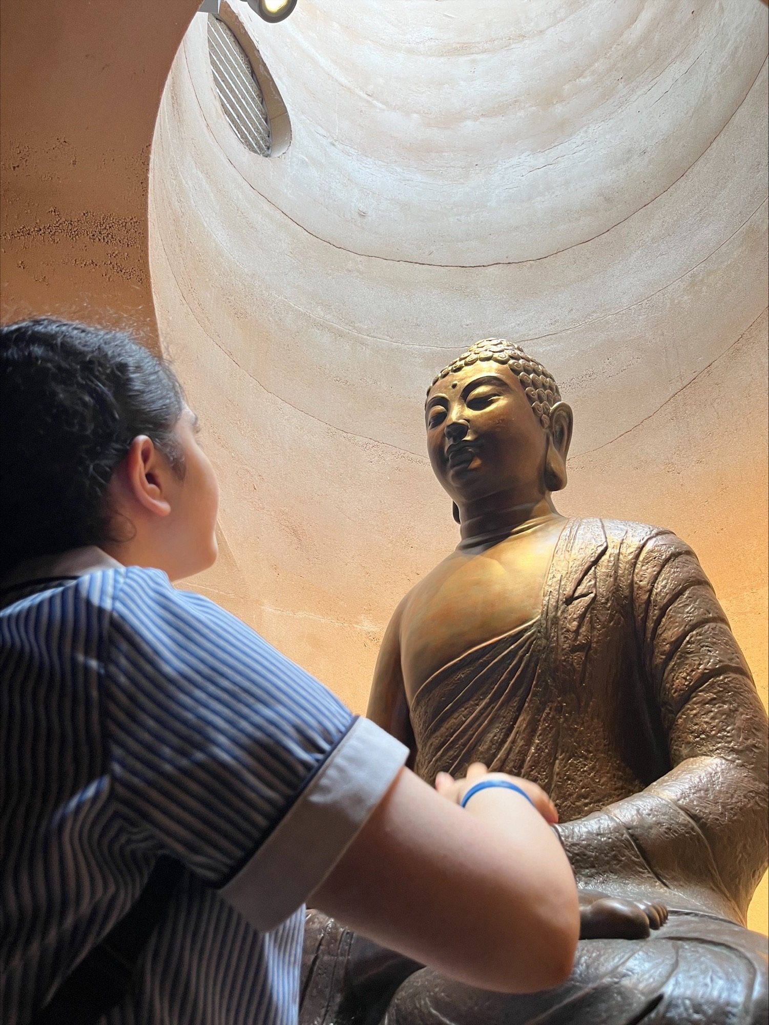 one of the students looking up at a scuplture of a buddah.jpeg