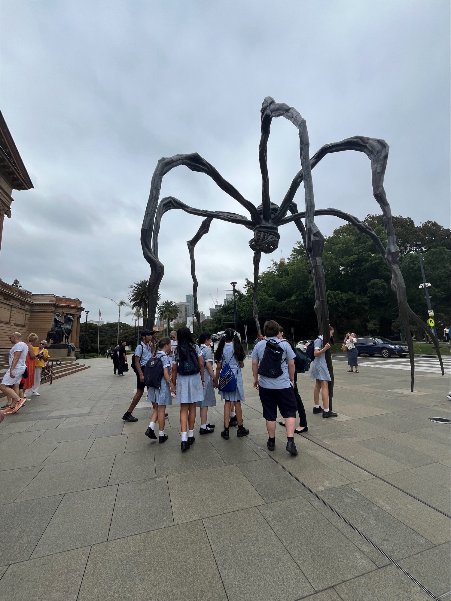 students looking at a very large outdoor abstract scuplture that looks like a spider.jpeg