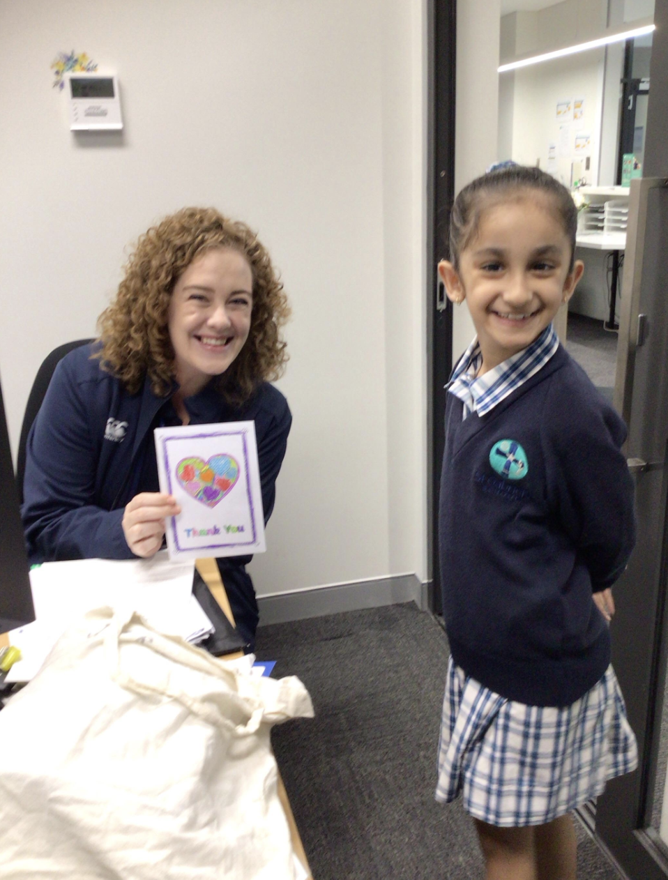 Mrs Bridge holding thank you card and smiling next to student.png
