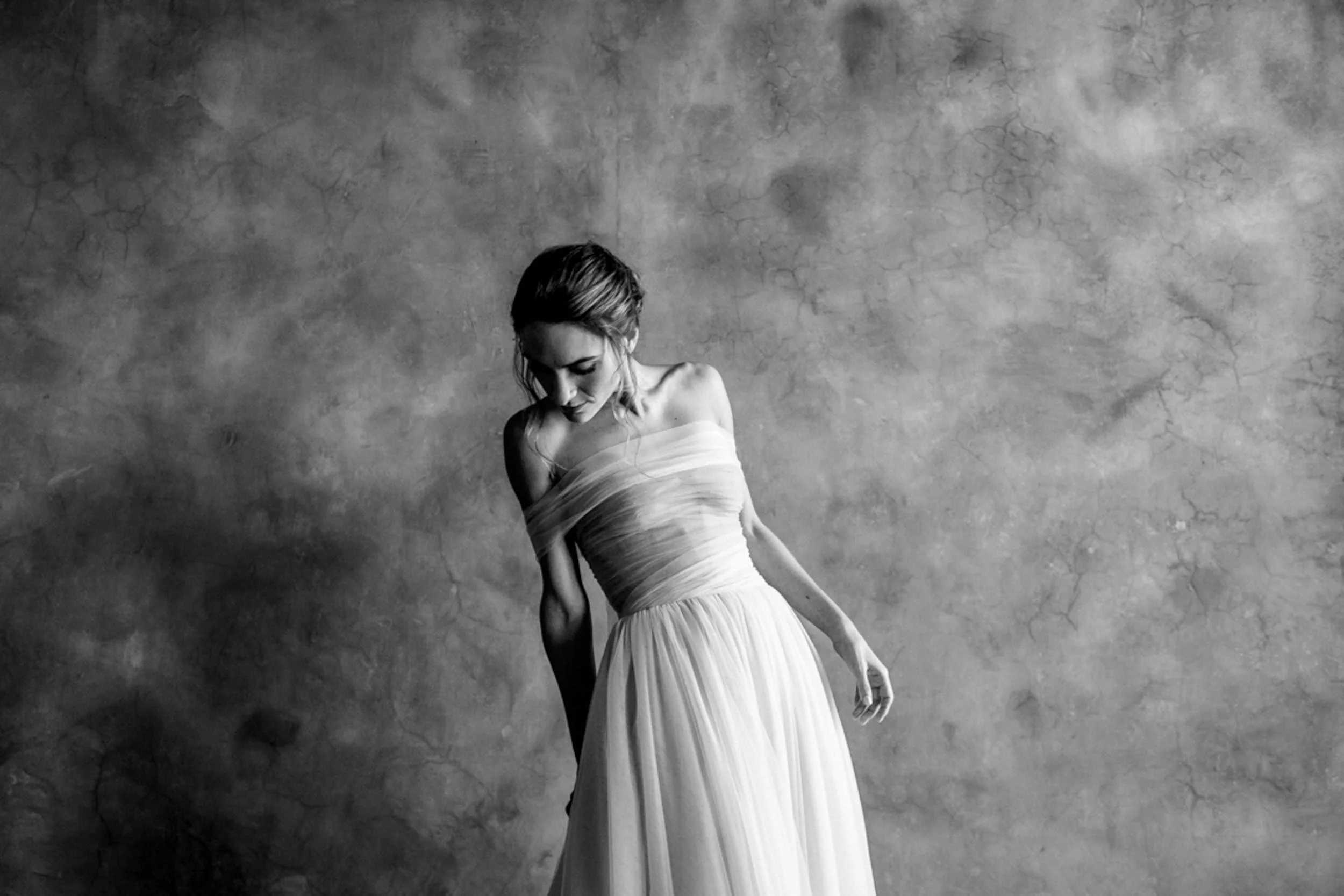 Mujer con vestido largo y elegante en un fondo de pared de tono gris