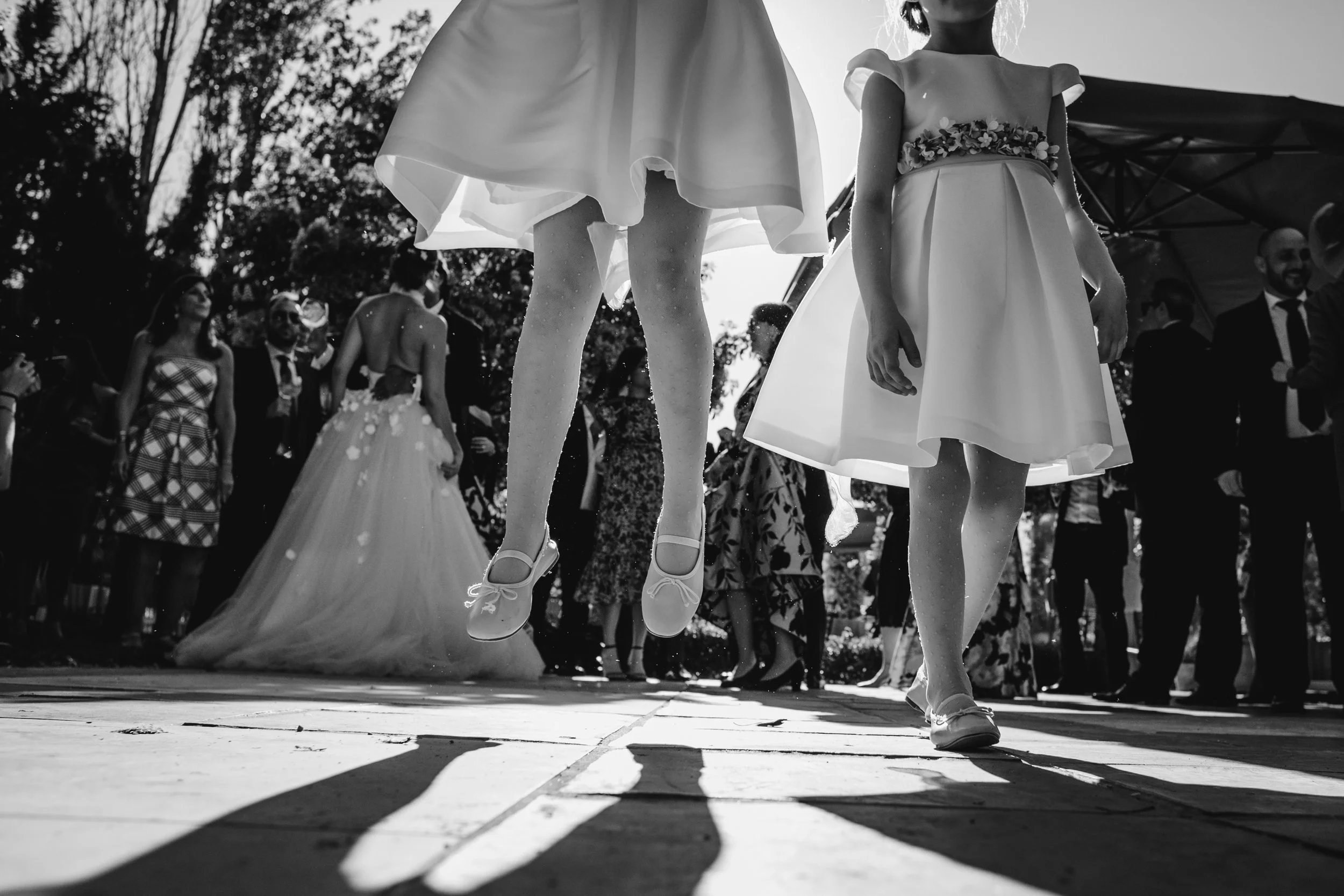 Niños bailando en una celebración al aire libre, vestidos con ropa formal y zapatos de charol.