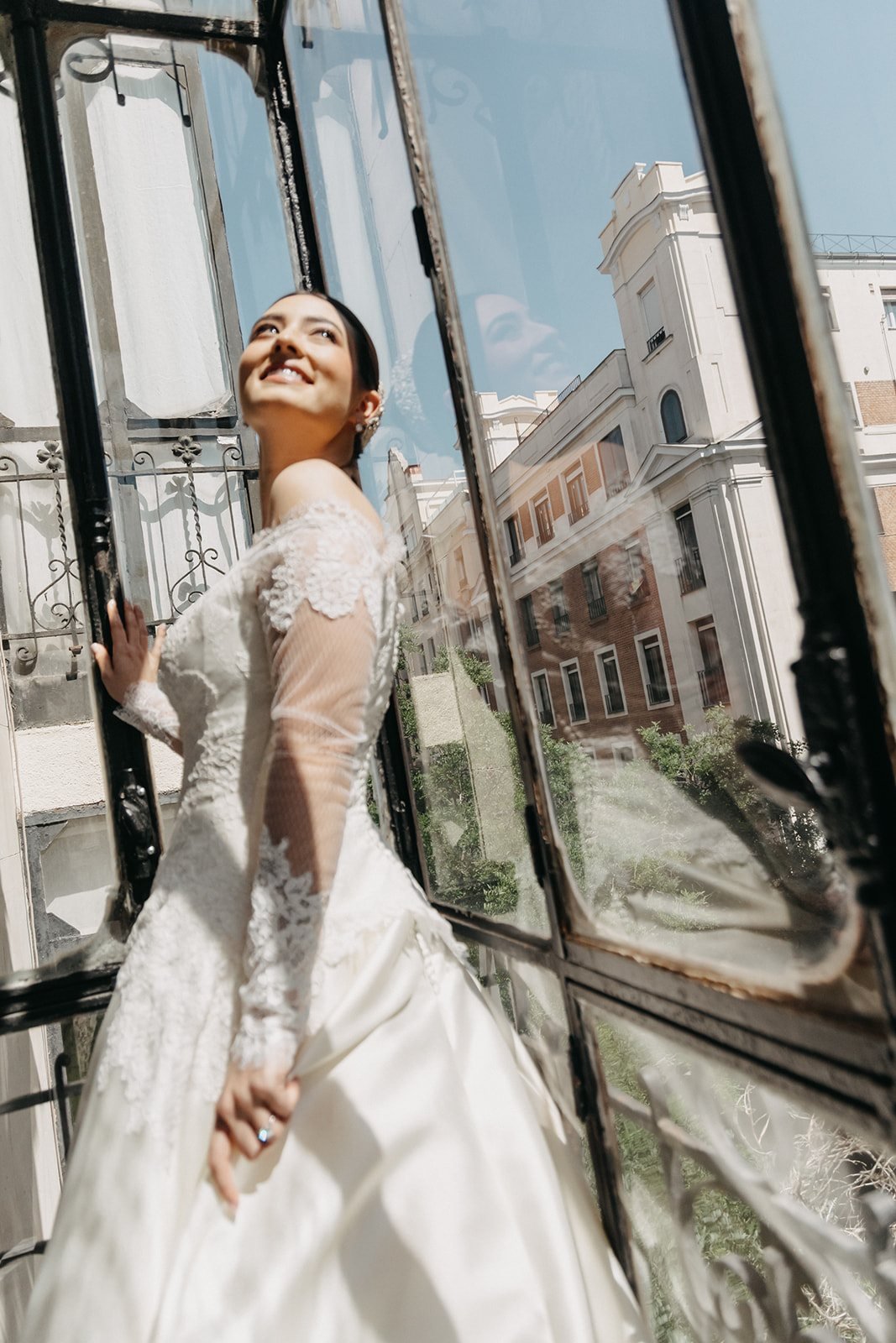 The bride leaning out of a window above the Madrid rooftops