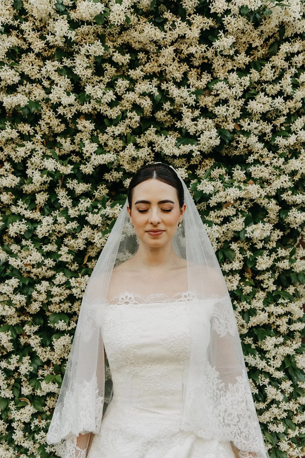 Portrait of Isabella in her veil against a jasmine wall