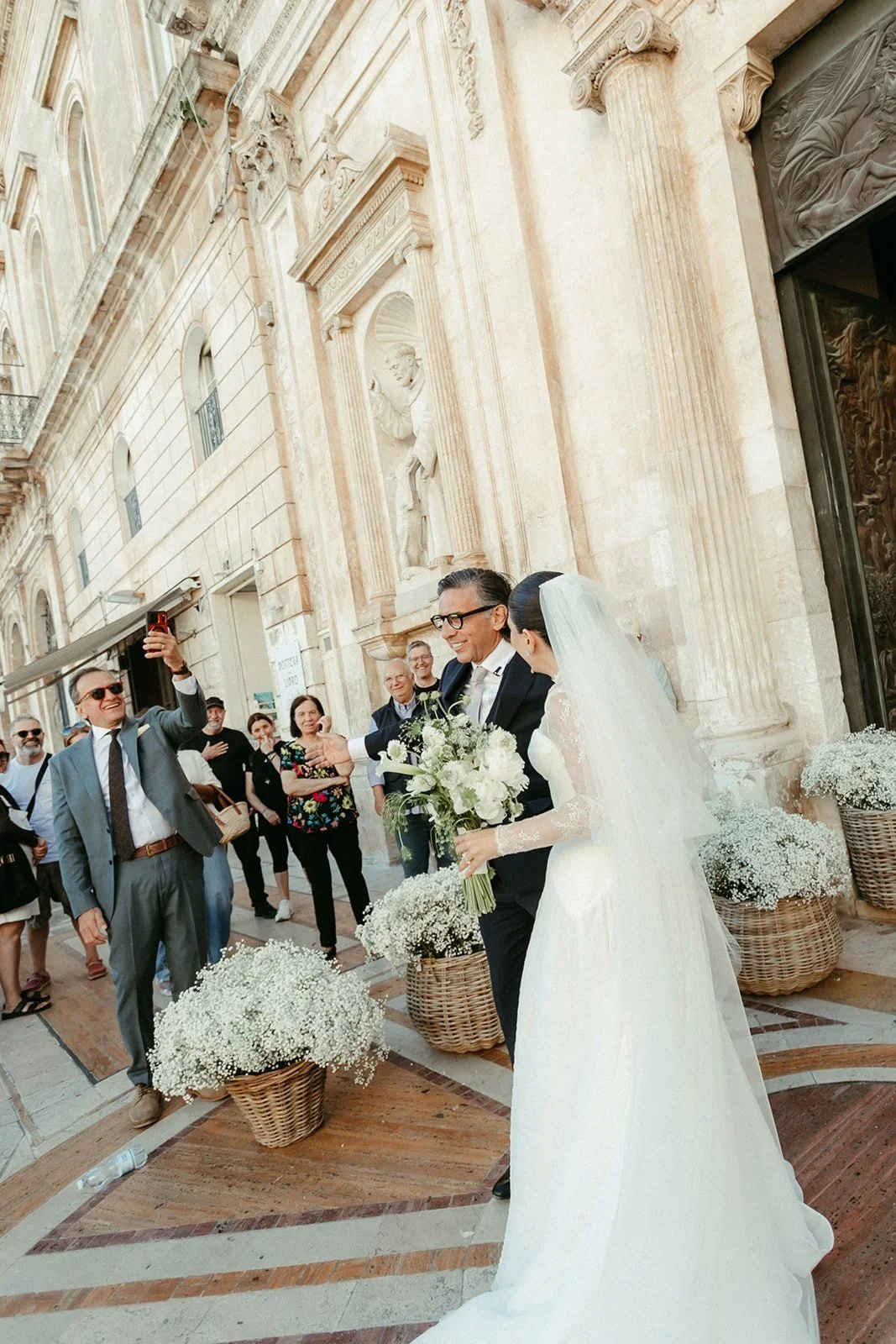 Llegada de la novia a la iglesia entre invitados y flores en Ostuni
