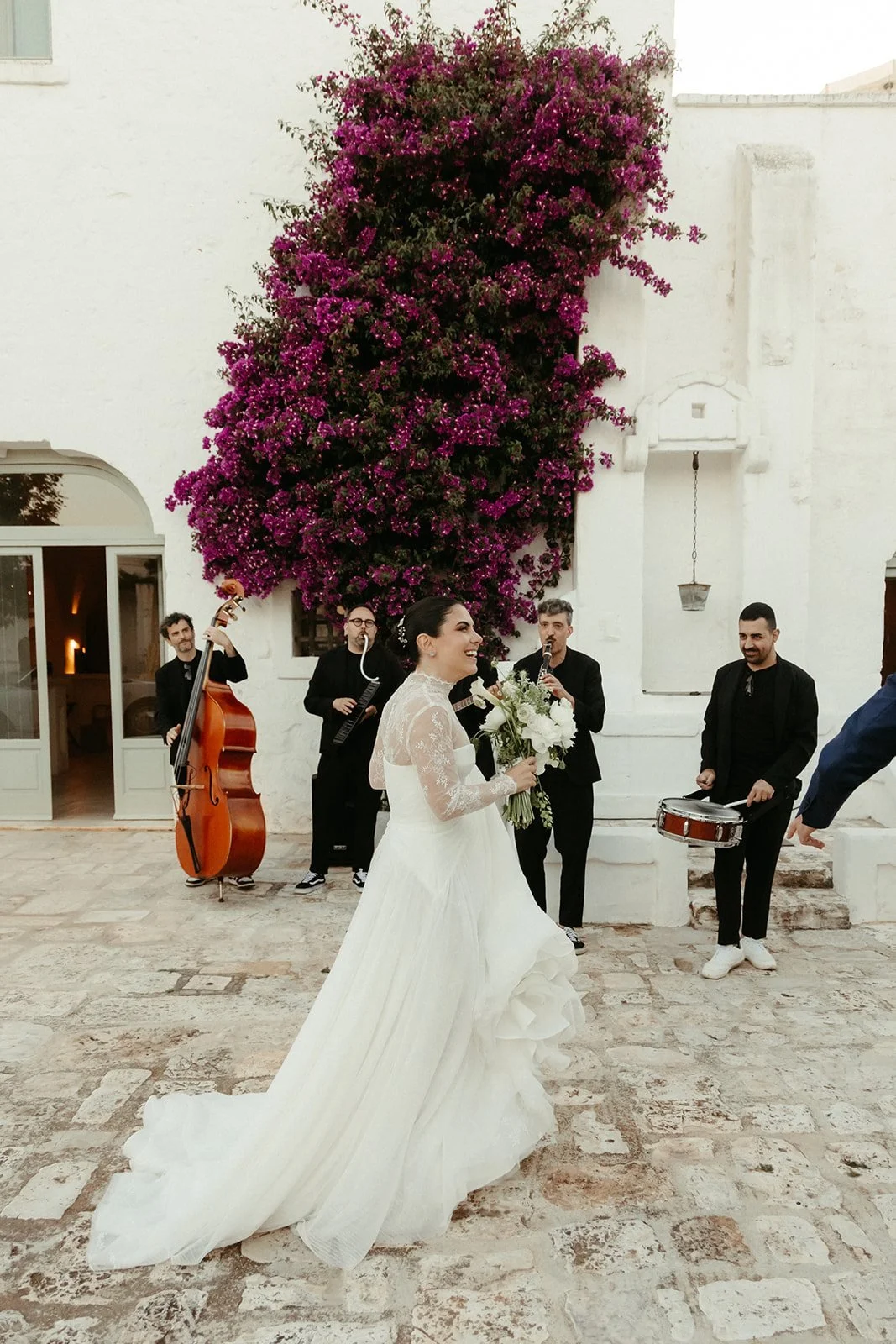 Los novios llegan a la masseria recibidos por músicos bajo la buganvilla