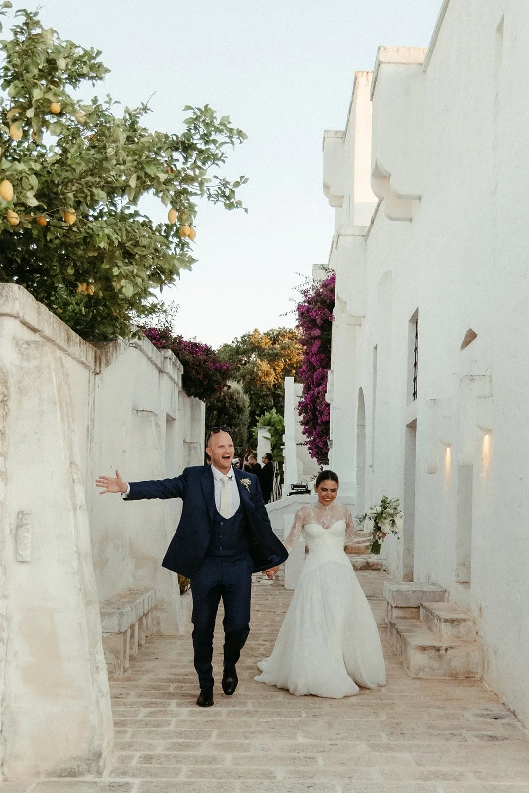 Los novios avanzan por un callejón blanco de la Masseria Le Carrube