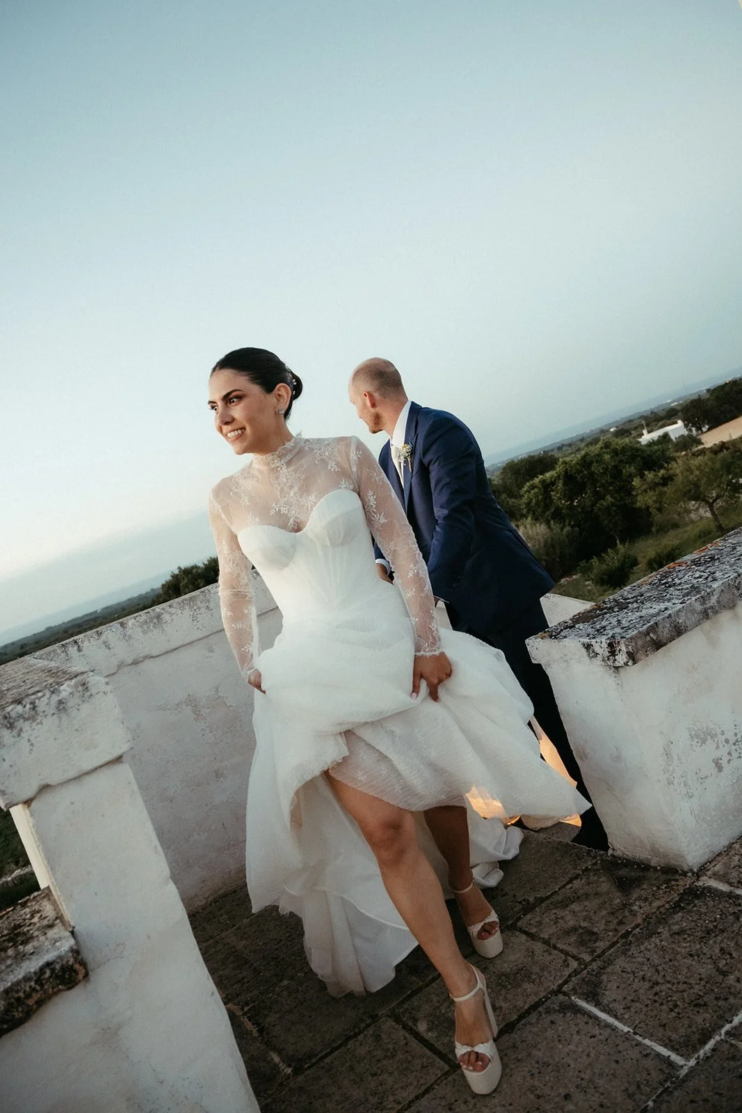 La novia en la azotea de la masseria al atardecer, con el campo de Puglia al fondo