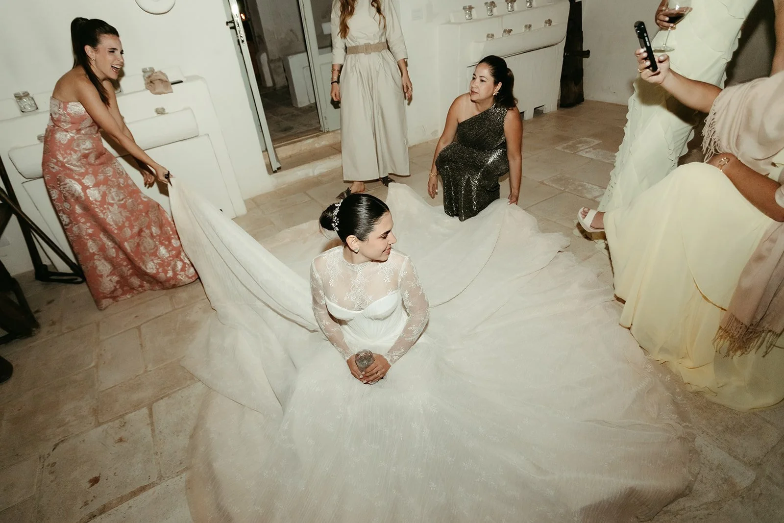 La novia sentada en la pista con el vestido extendido, rodeada de amigas