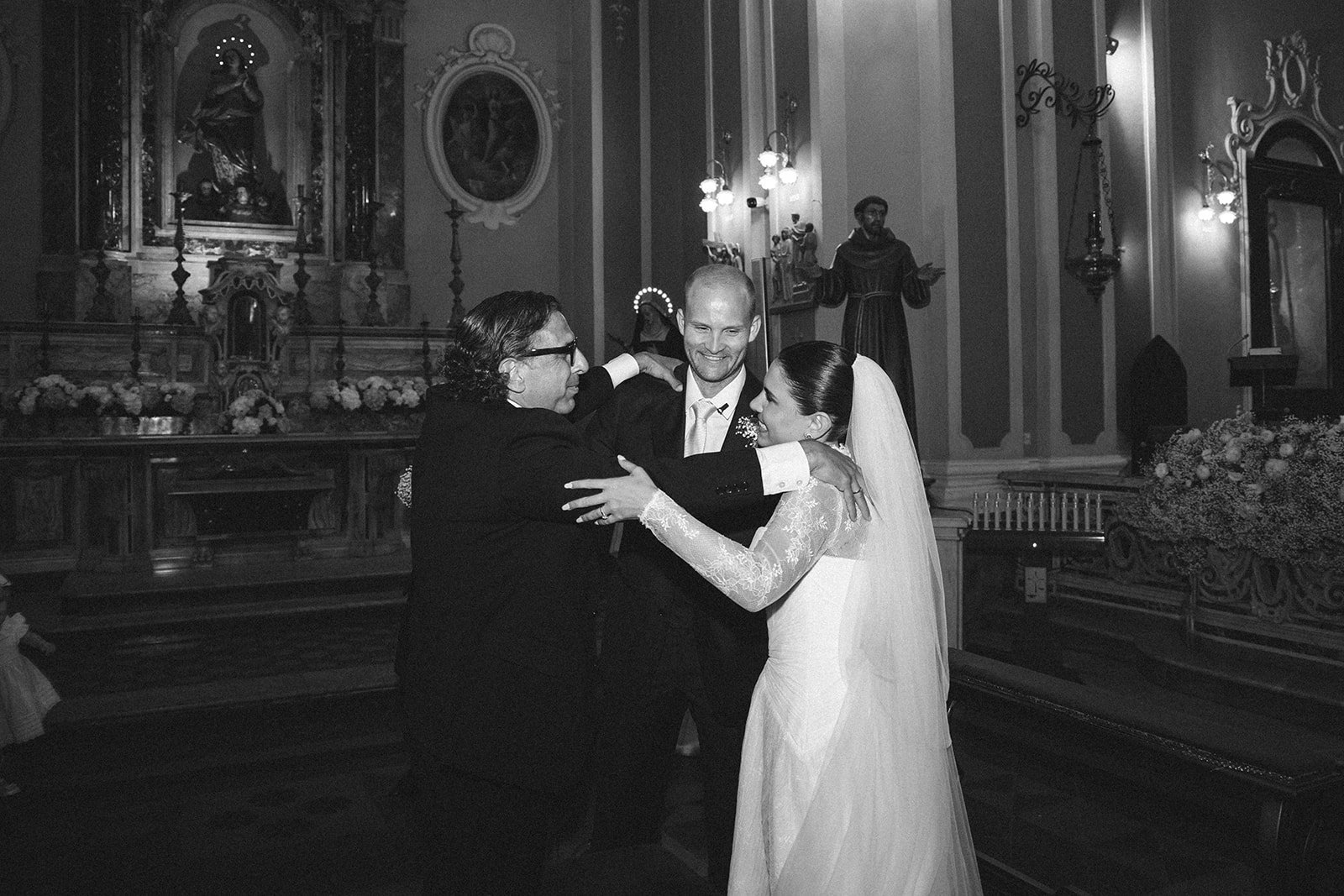 The newlyweds greeting guests inside the church, in black and white