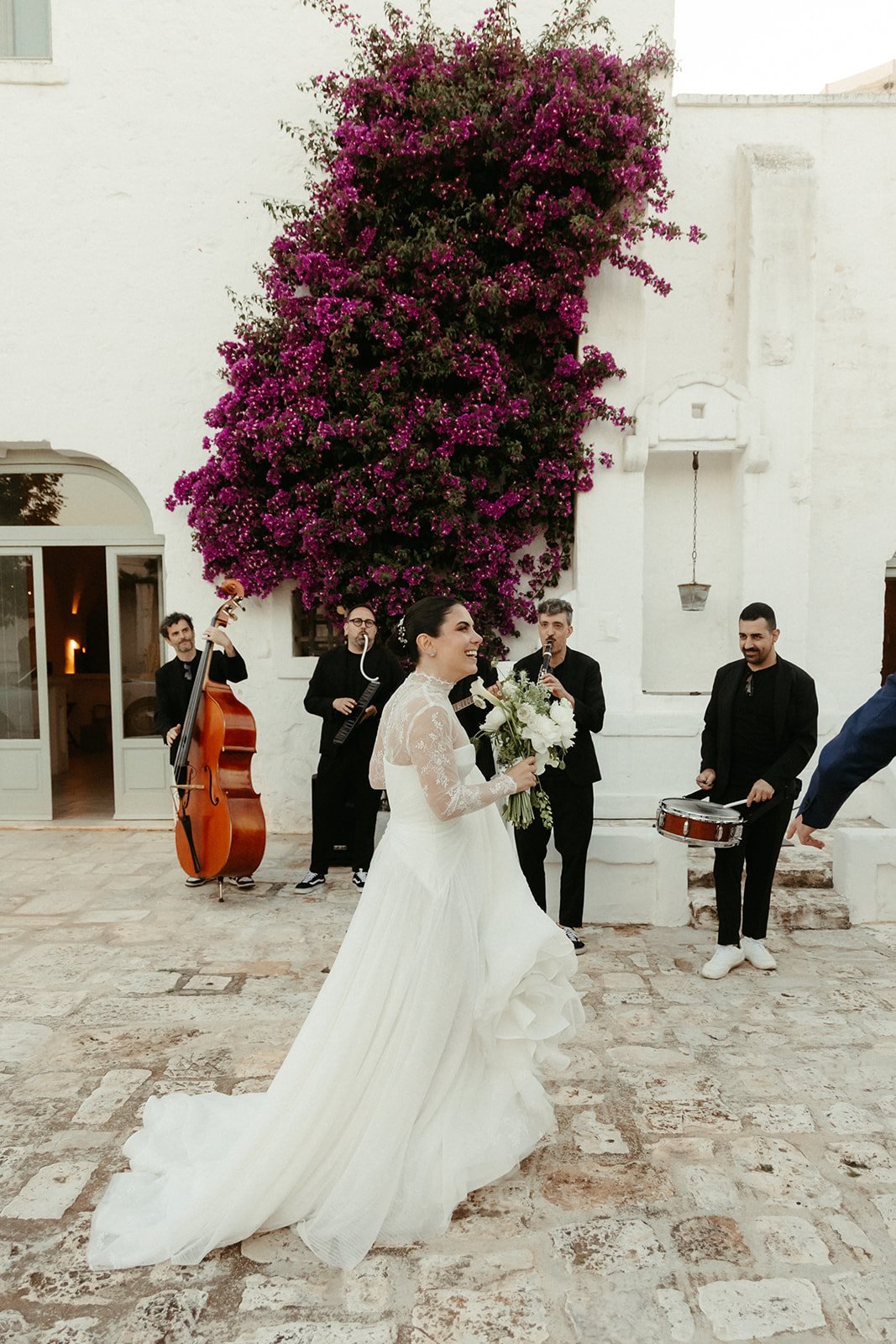 The couple welcomed at the masseria by musicians under the bougainvillea