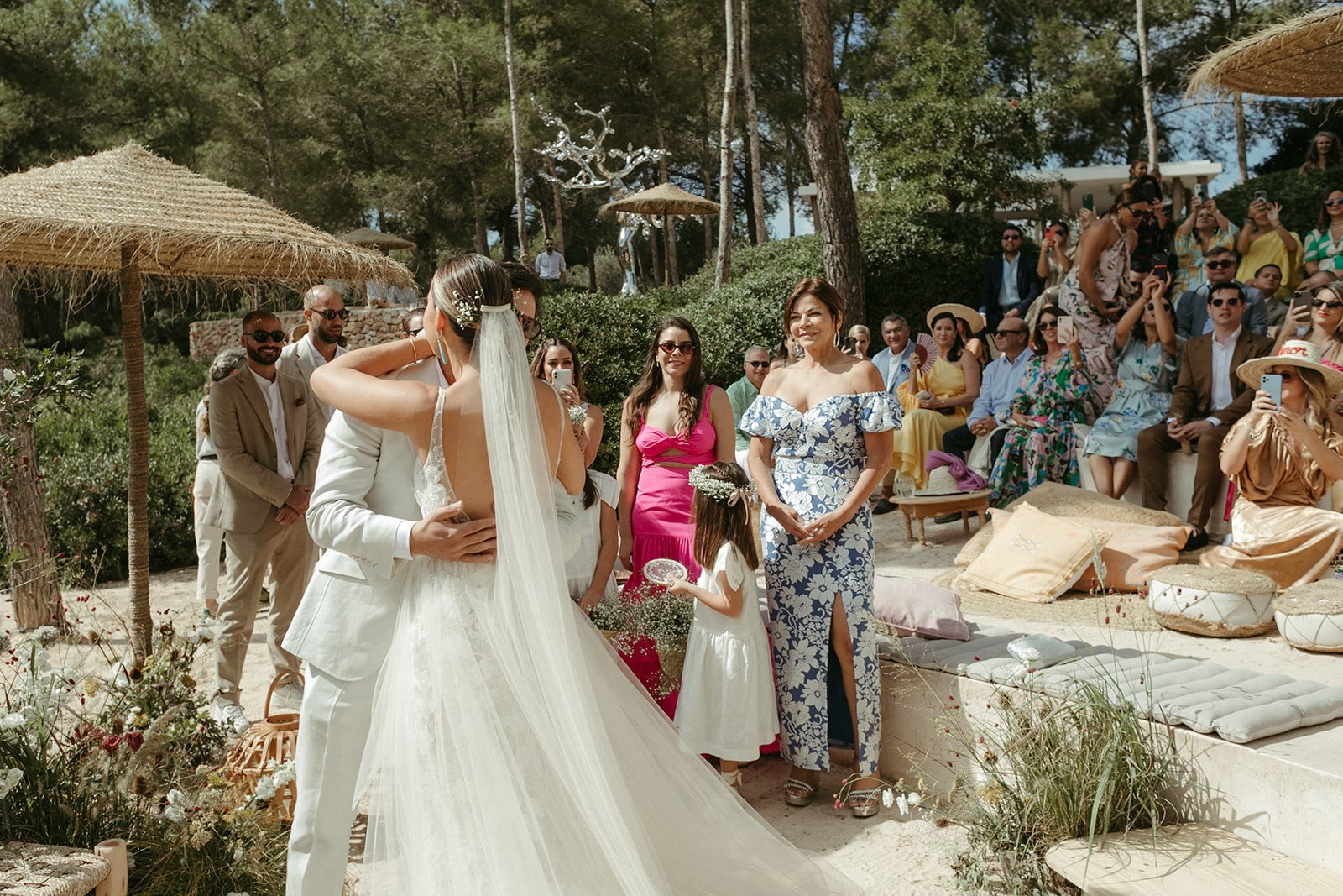 La novia llega a la ceremonia entre sombrillas de paja e invitados
