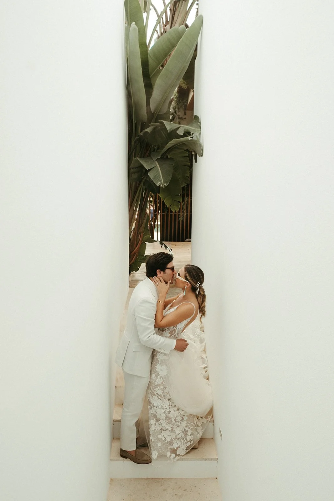 Beso de los novios en el pasillo blanco entre plataneras