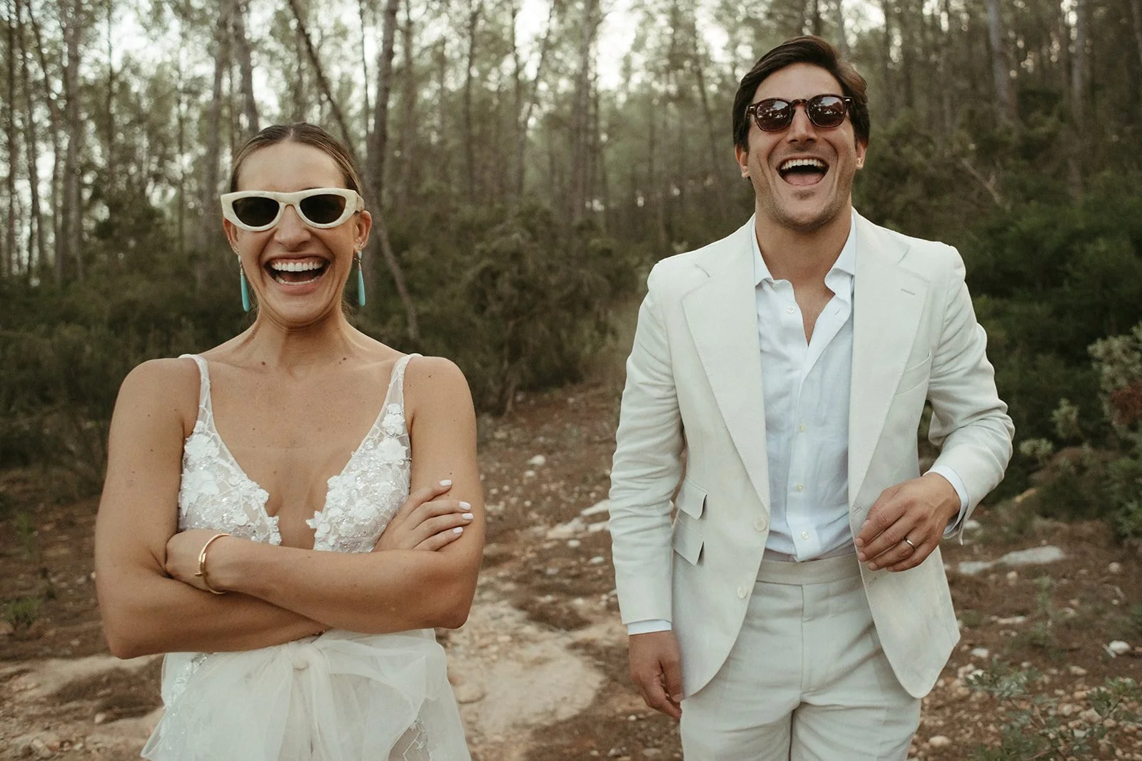 Mafe y Leo, de brazos cruzados y riendo, en el bosque