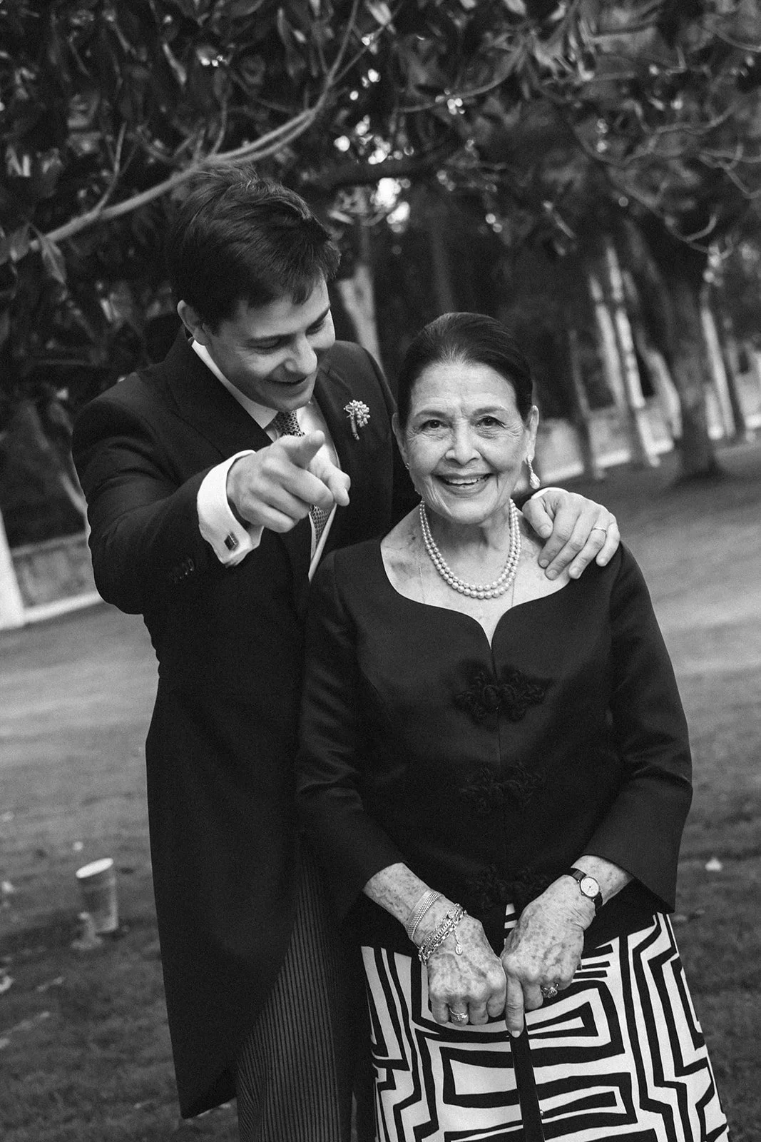 Candid laughter between the groom and a guest, in black and white