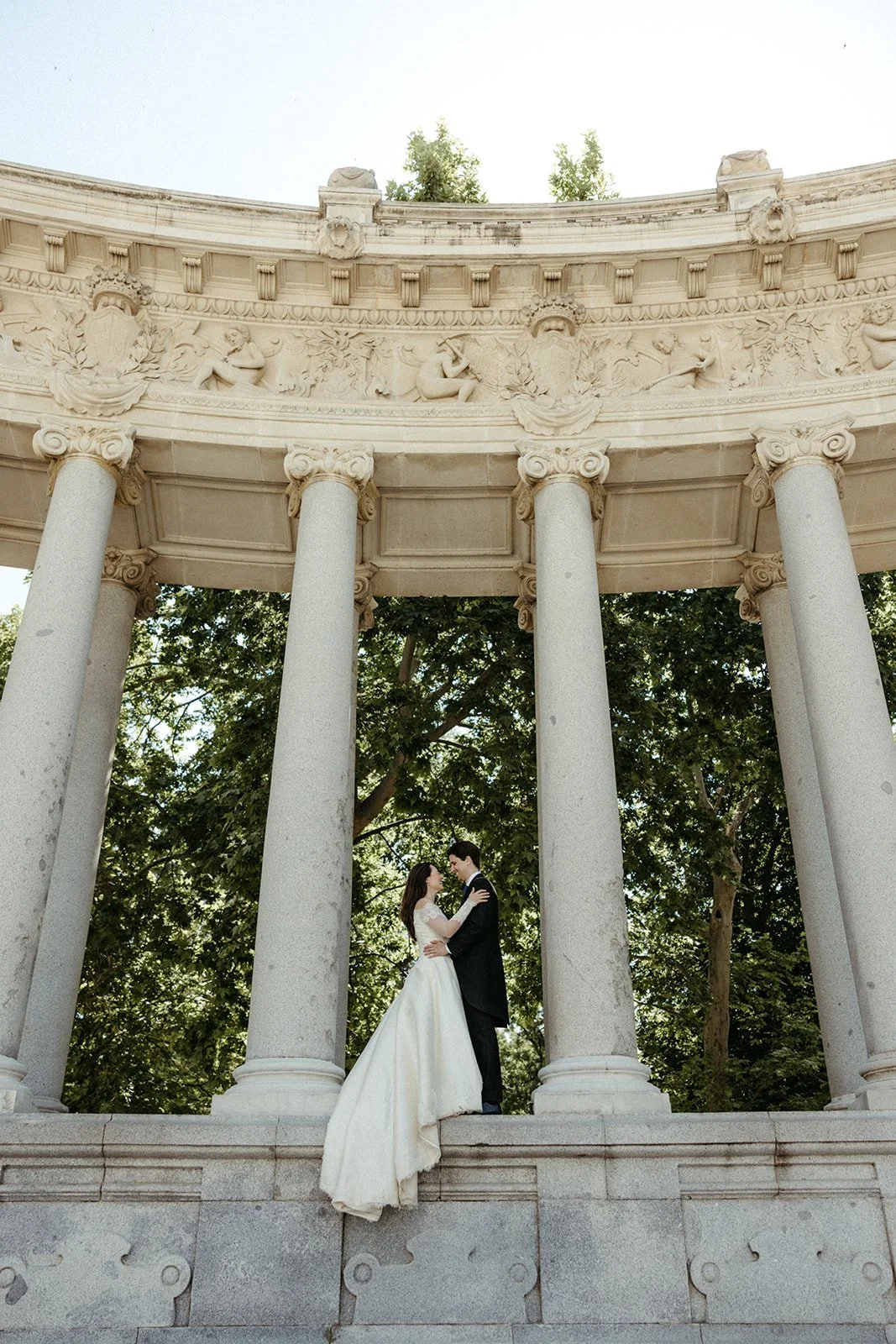 Los novios bajo una columnata de piedra en la sesión de postboda