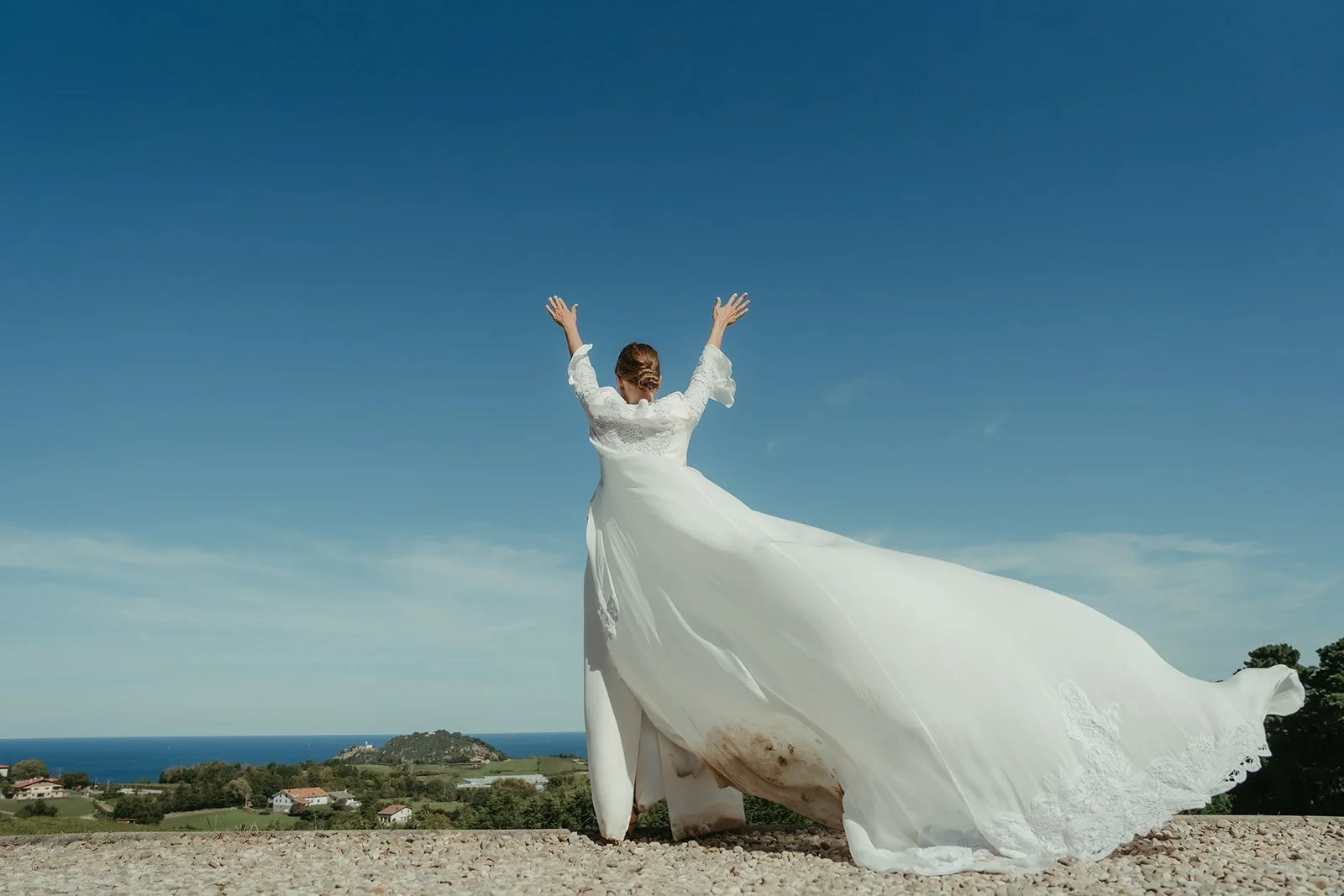 Amalia con los brazos en alto y el vestido al viento frente al mar
