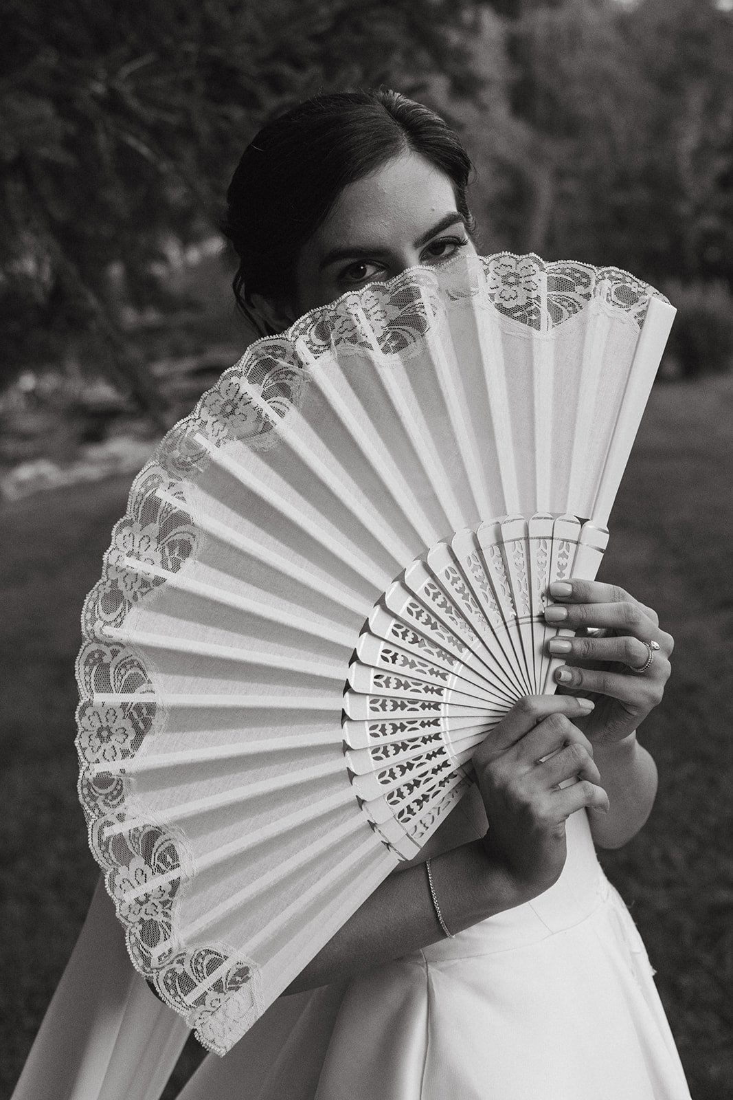 Sabrina se tapa la cara con un abanico de encaje, en blanco y negro