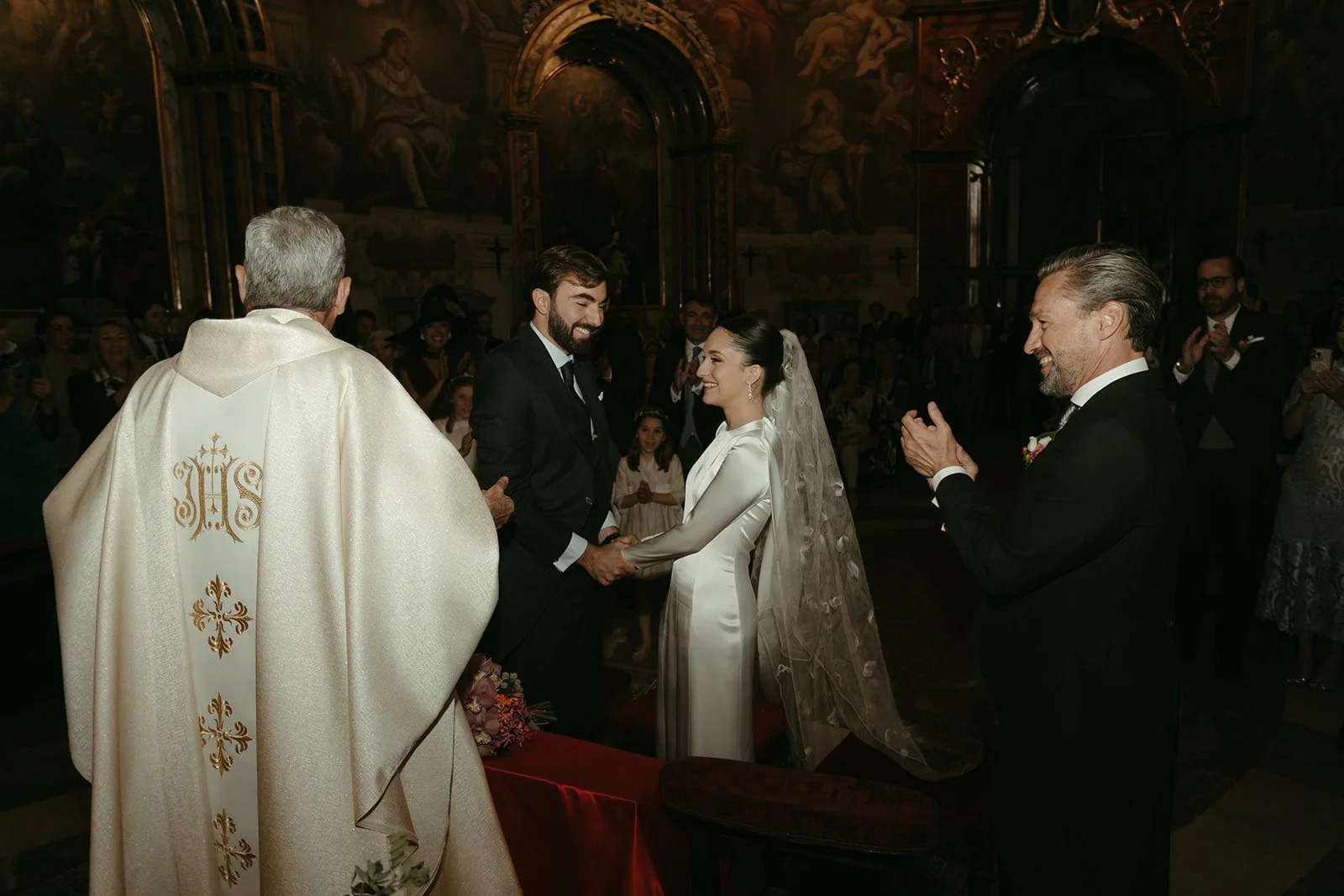 El sacerdote frente a Emiliana y Emilio en el altar, boda en Madrid