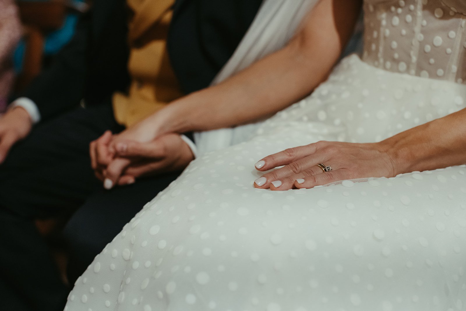 La mano de la novia con el anillo, sobre el vestido