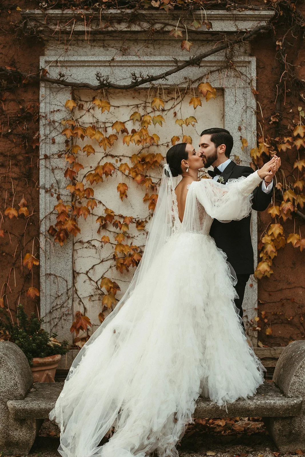 Bride and groom kissing in front of an autumn ivy wall at a wedding estate in Madrid