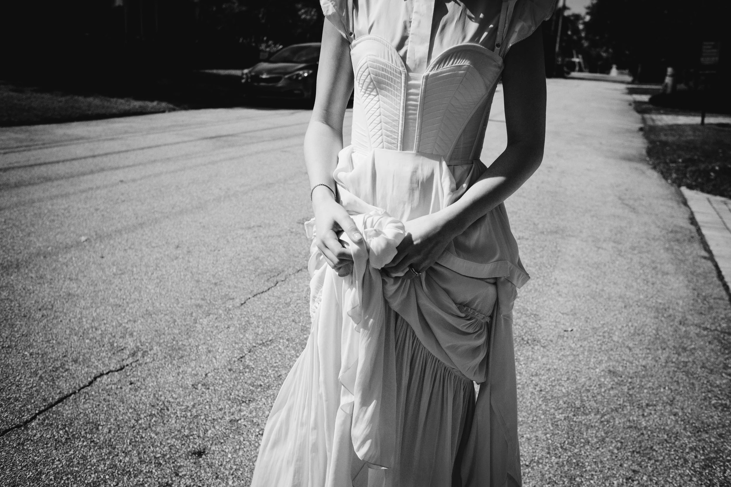 Mujer en vestido largo y corset caminando por la calle, de espaldas.