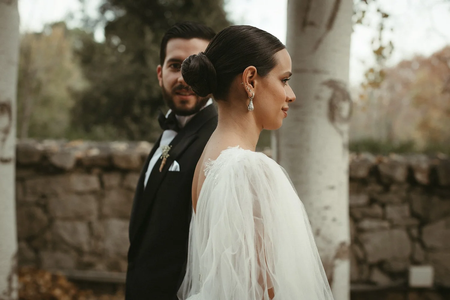 Bride and groom side by side in front of an old stone wall at their wedding estate in Madrid