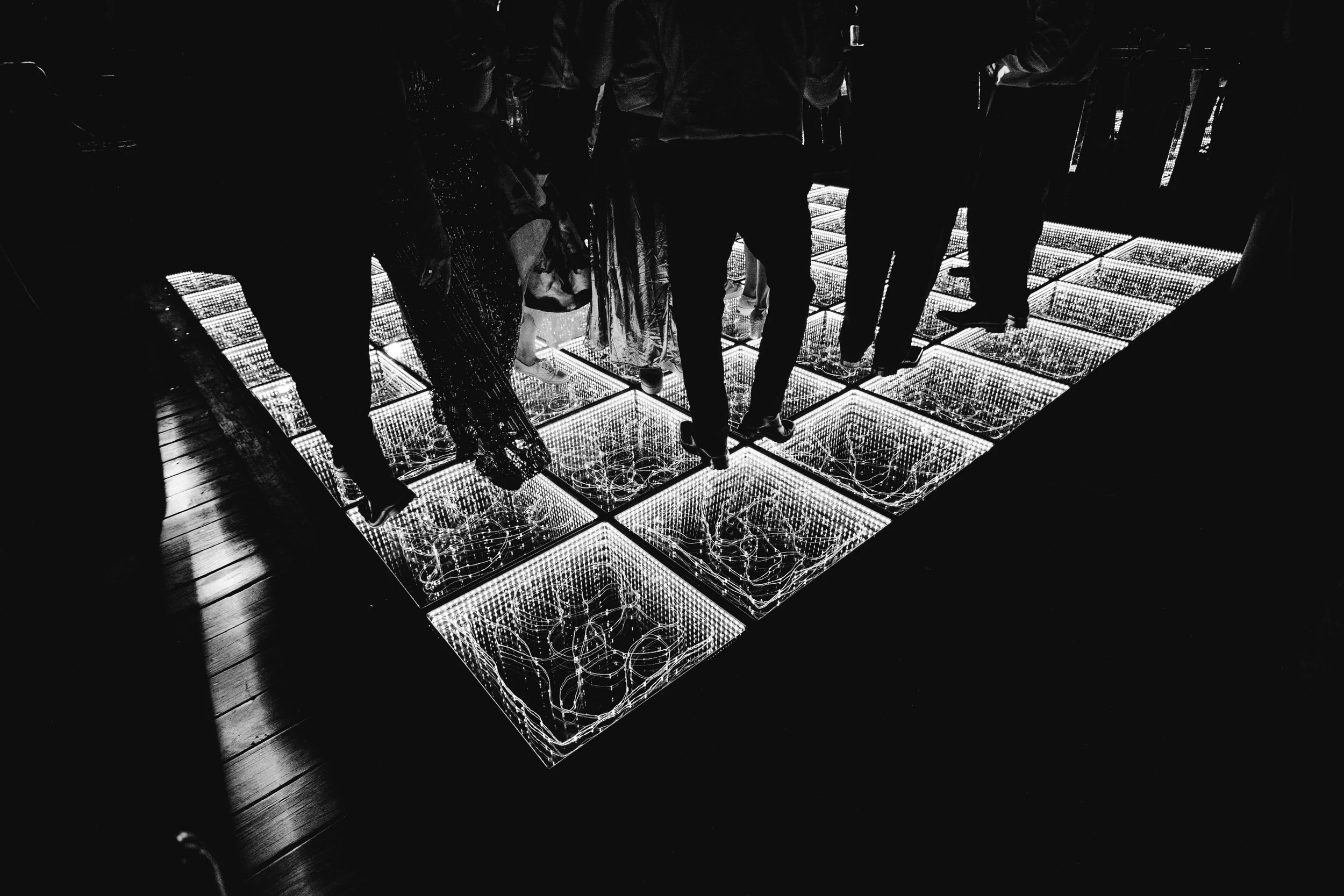 Persona en un piso de vidrio iluminado con luces LED, en un evento nocturno.