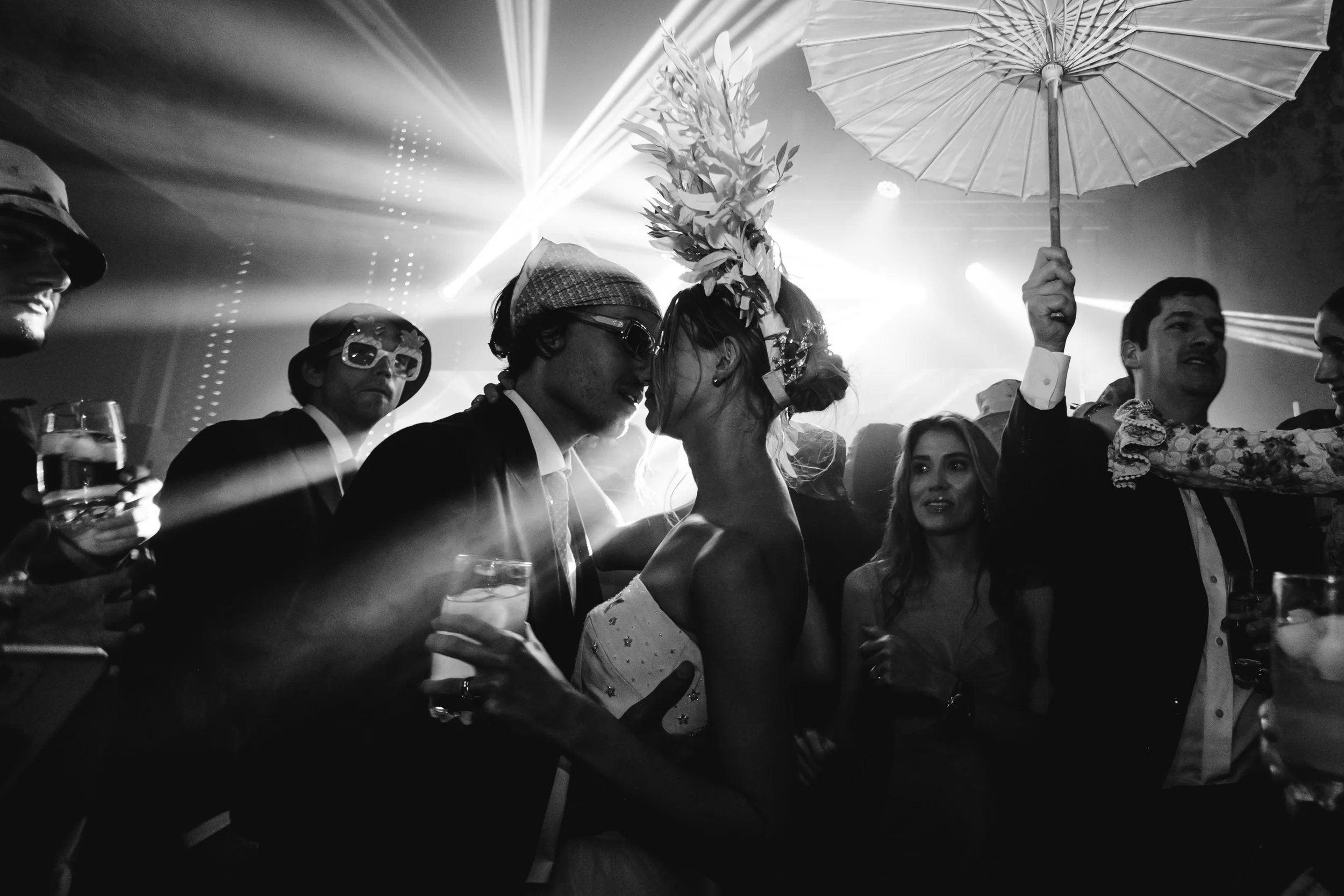 Firma de novios en una pista de baile en una boda, con invitados alrededor y iluminación de discoteca.
