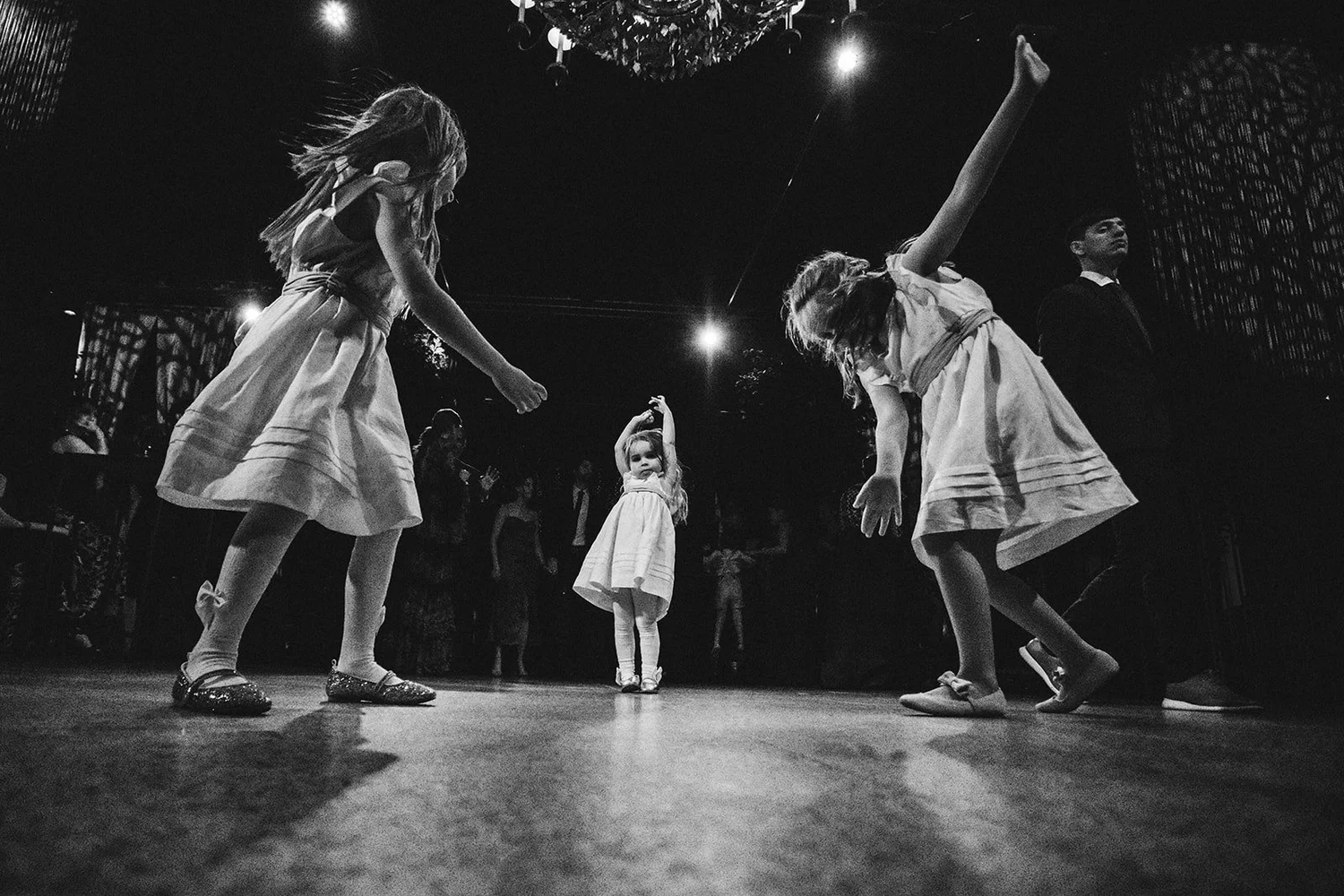 Black and white photo of flower girls dancing on the dance floor at a wedding in Madrid