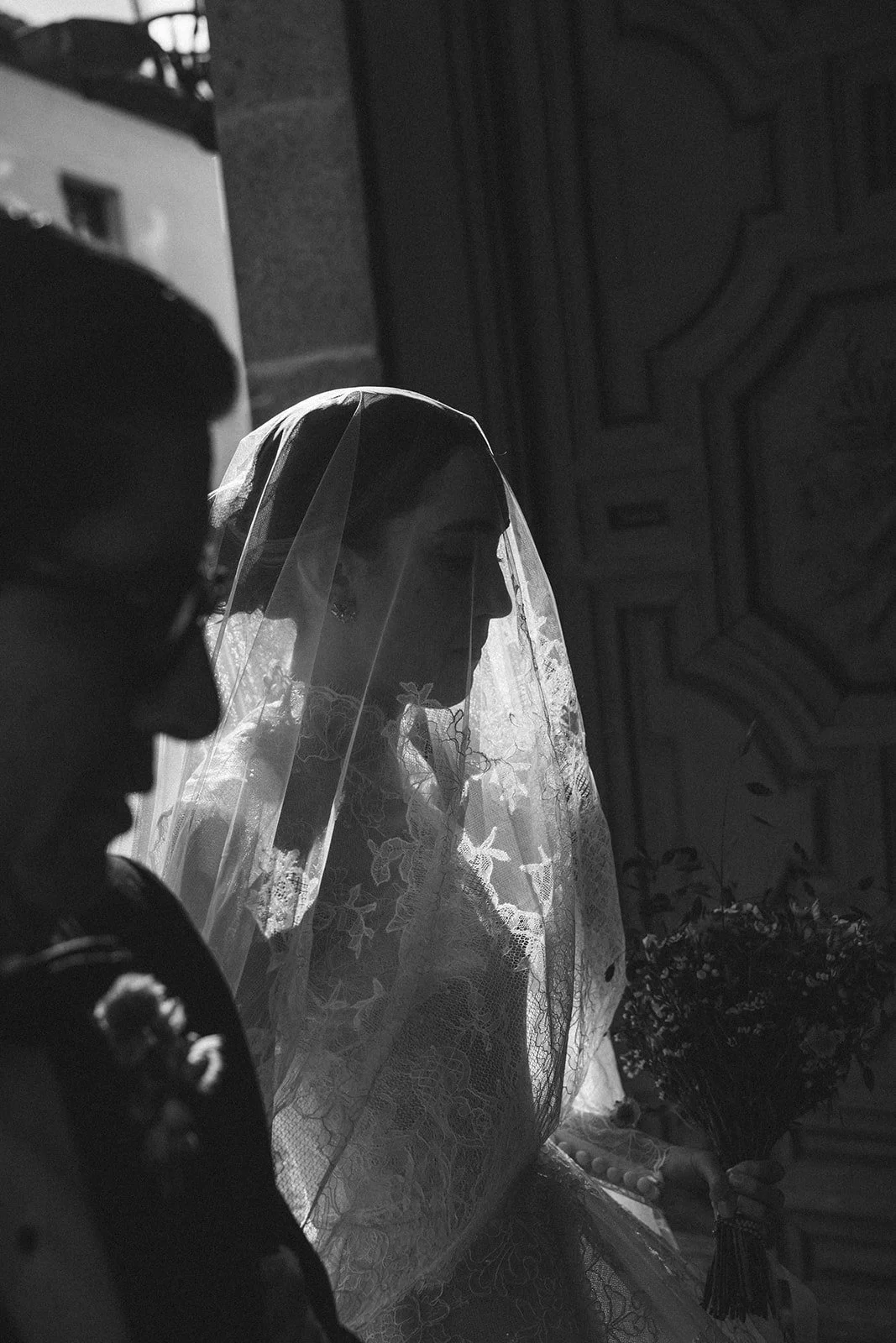 Black and white photo of the bride under her lace veil at the church door on her wedding day in Madrid