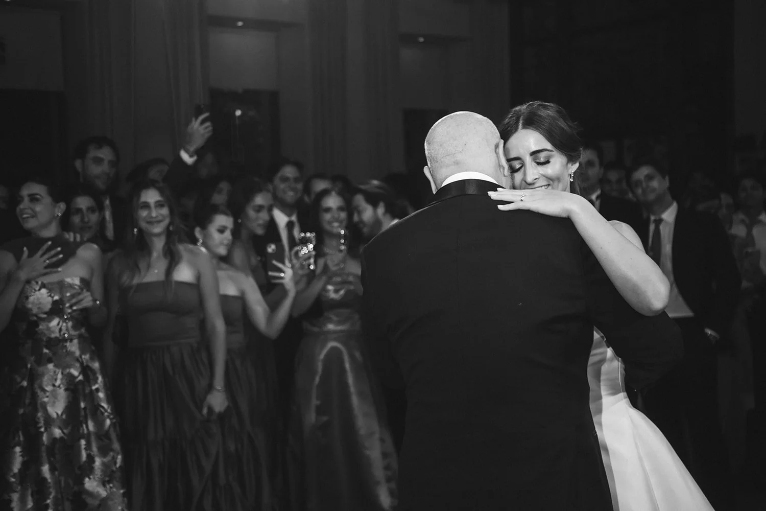 Black and white photo of the bride dancing with her father as guests watch at her Madrid wedding