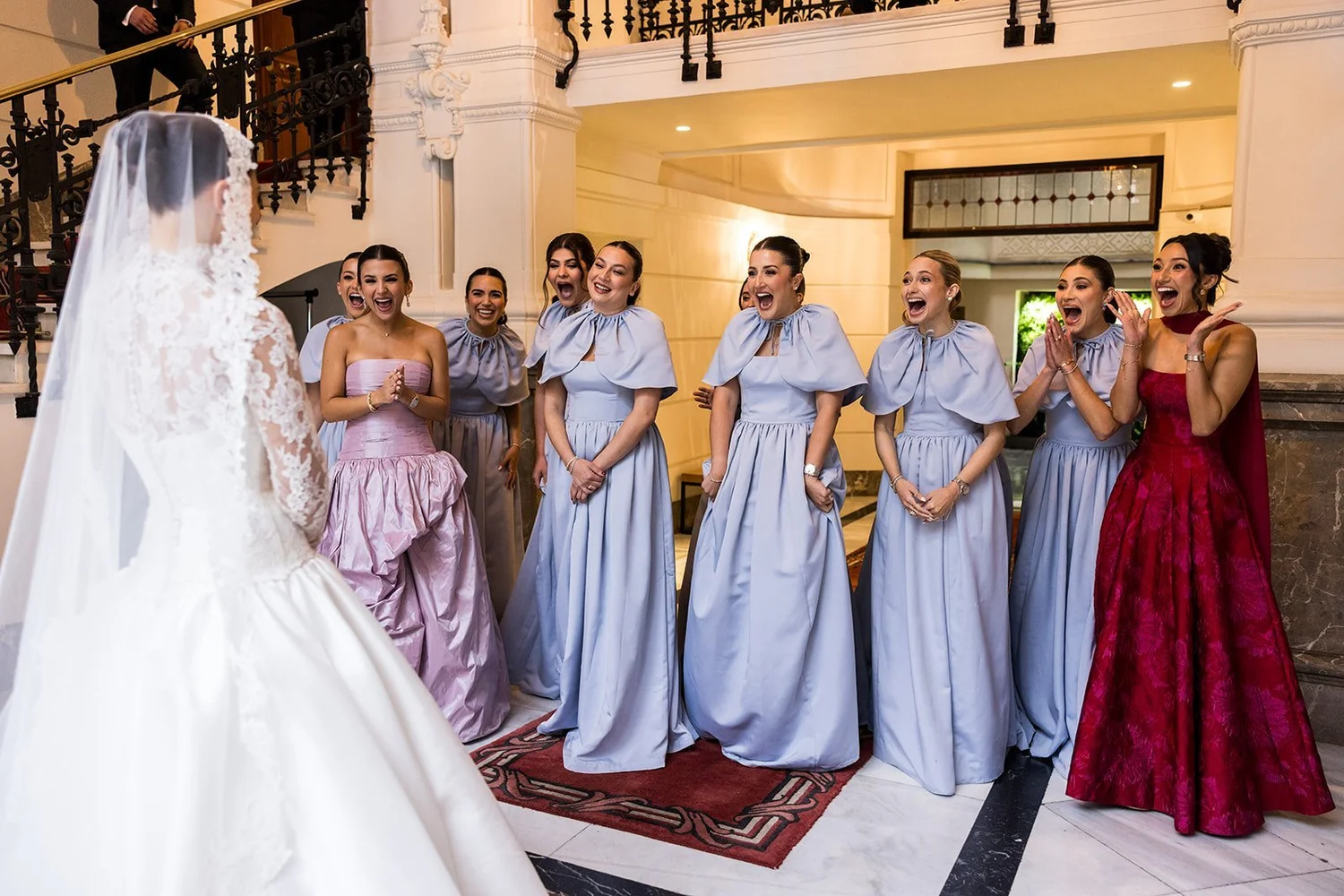 Bridesmaids in pale blue gowns reacting as they see the bride for the first time, Madrid wedding