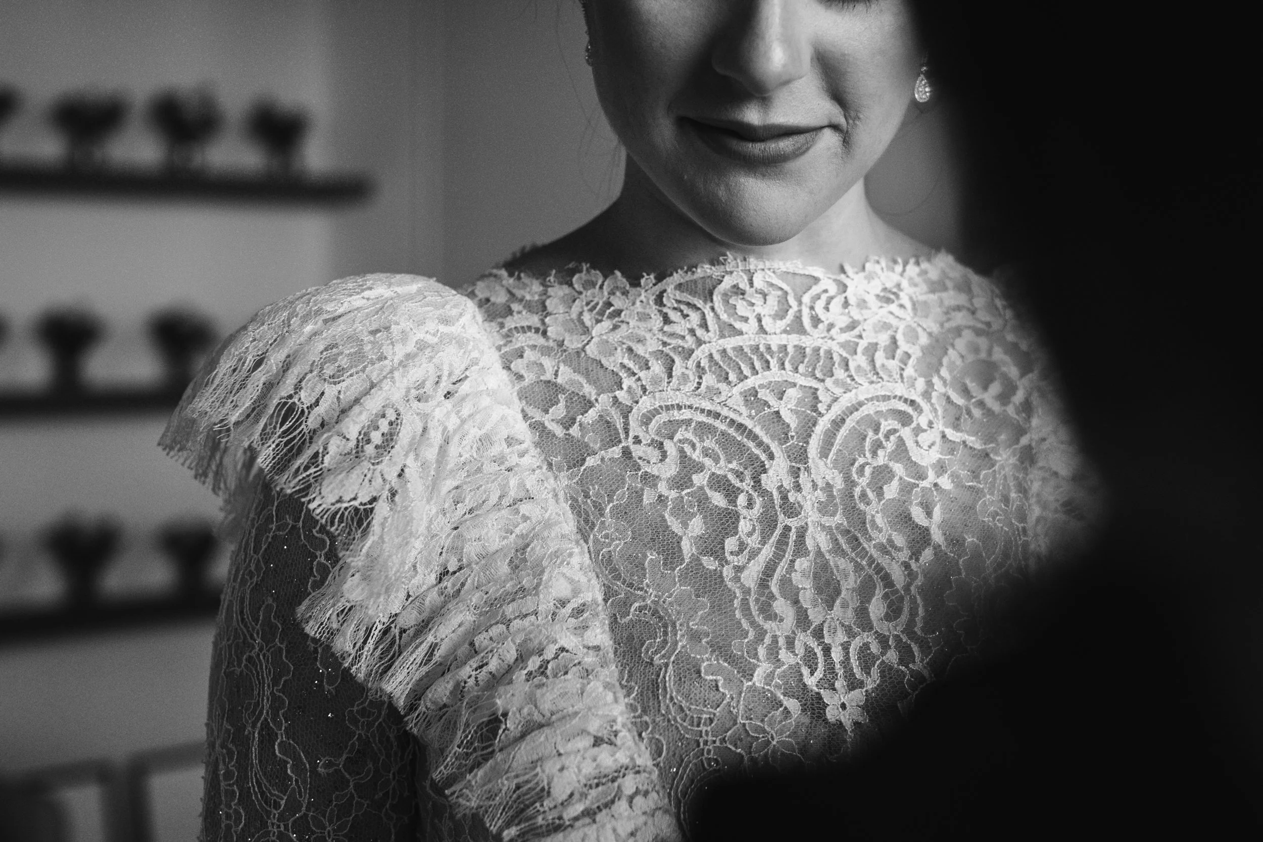 Mujer con vestido de encaje blanco, sonrisa, pendientes, en un ambiente interior.
