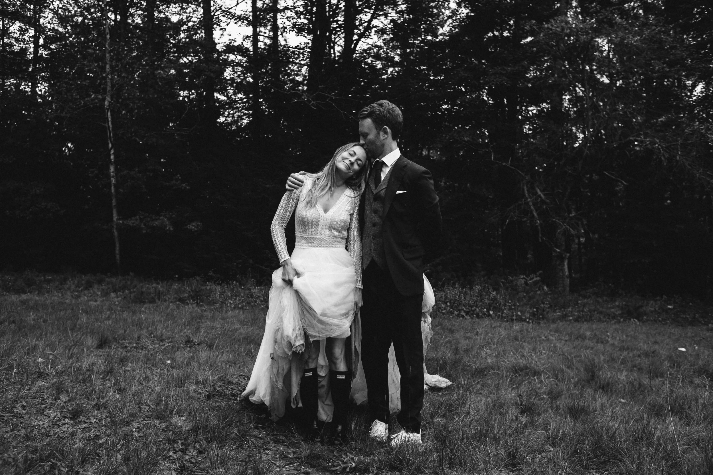 Una pareja en una boda, con la mujer con vestido de novia y el hombre con traje, en un entorno natural, en blanco y negro.