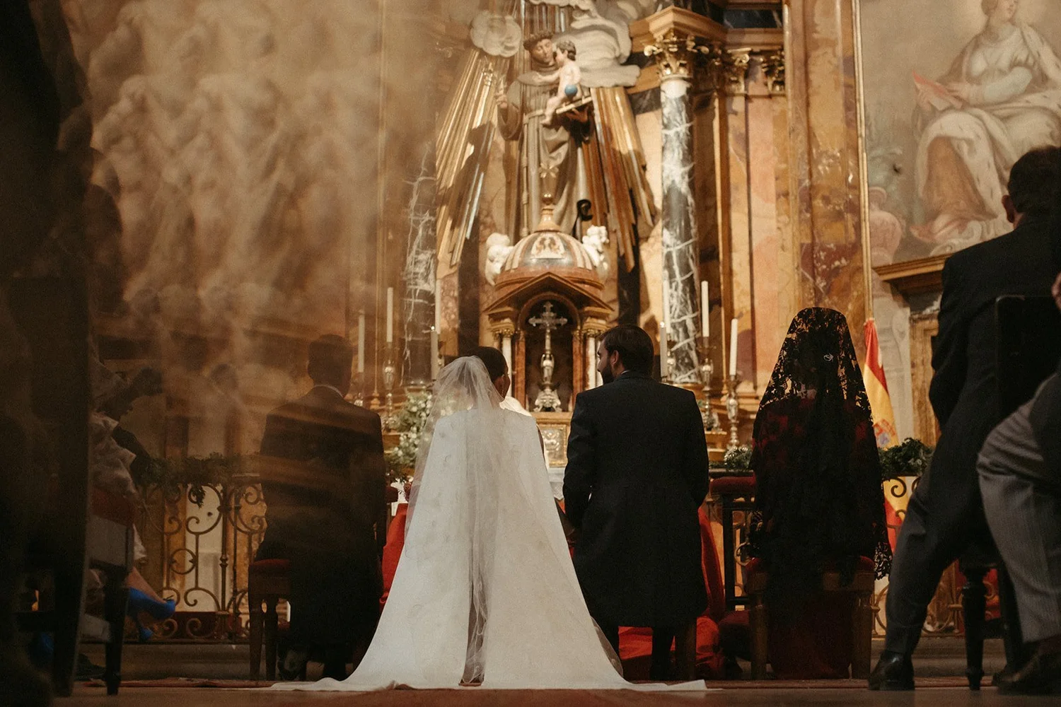 Bride and groom at a gilded baroque altar during the church ceremony of their wedding in Madrid