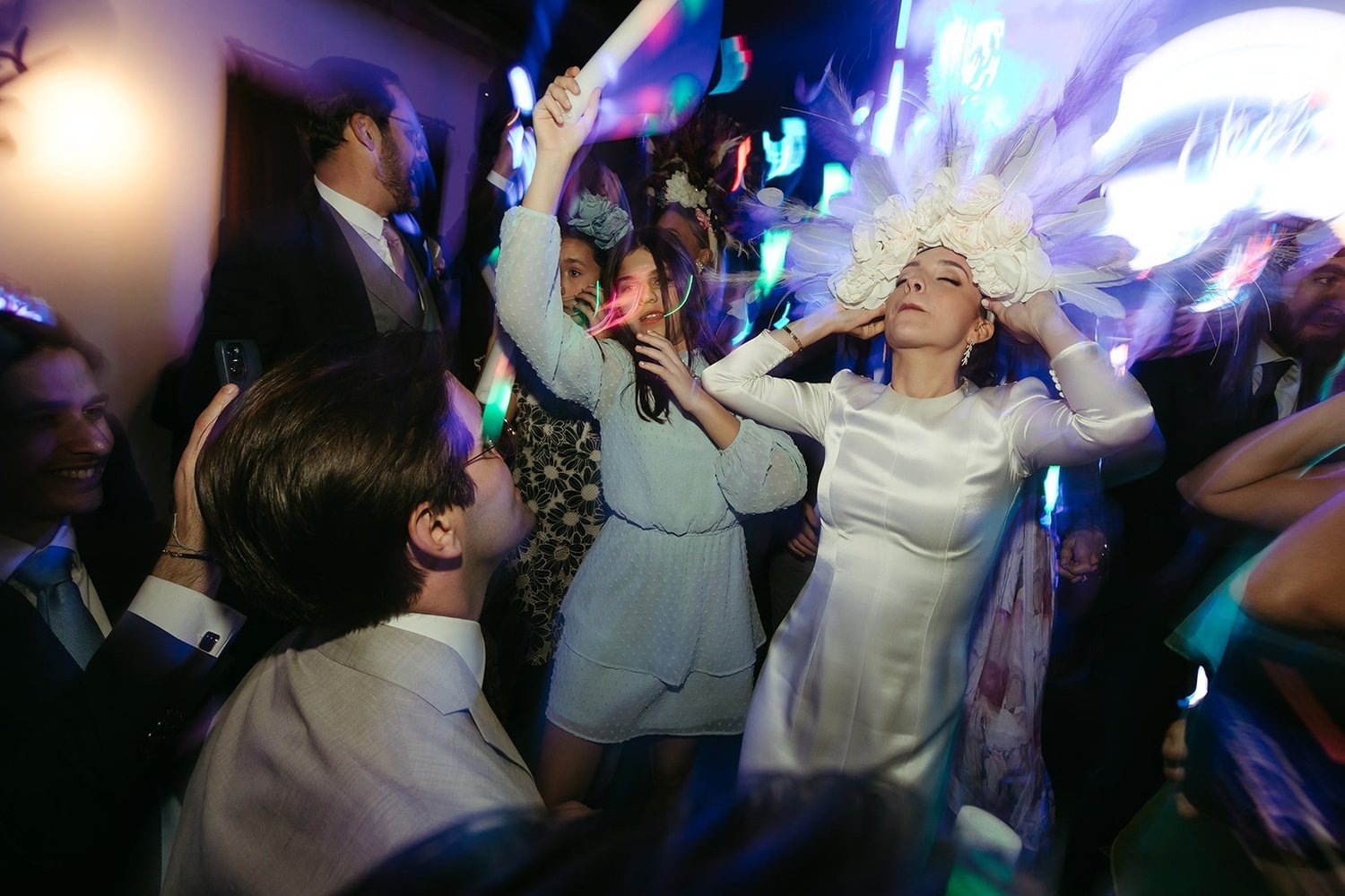 Bride dancing in a white feather headdress with her guests at her wedding party in Madrid