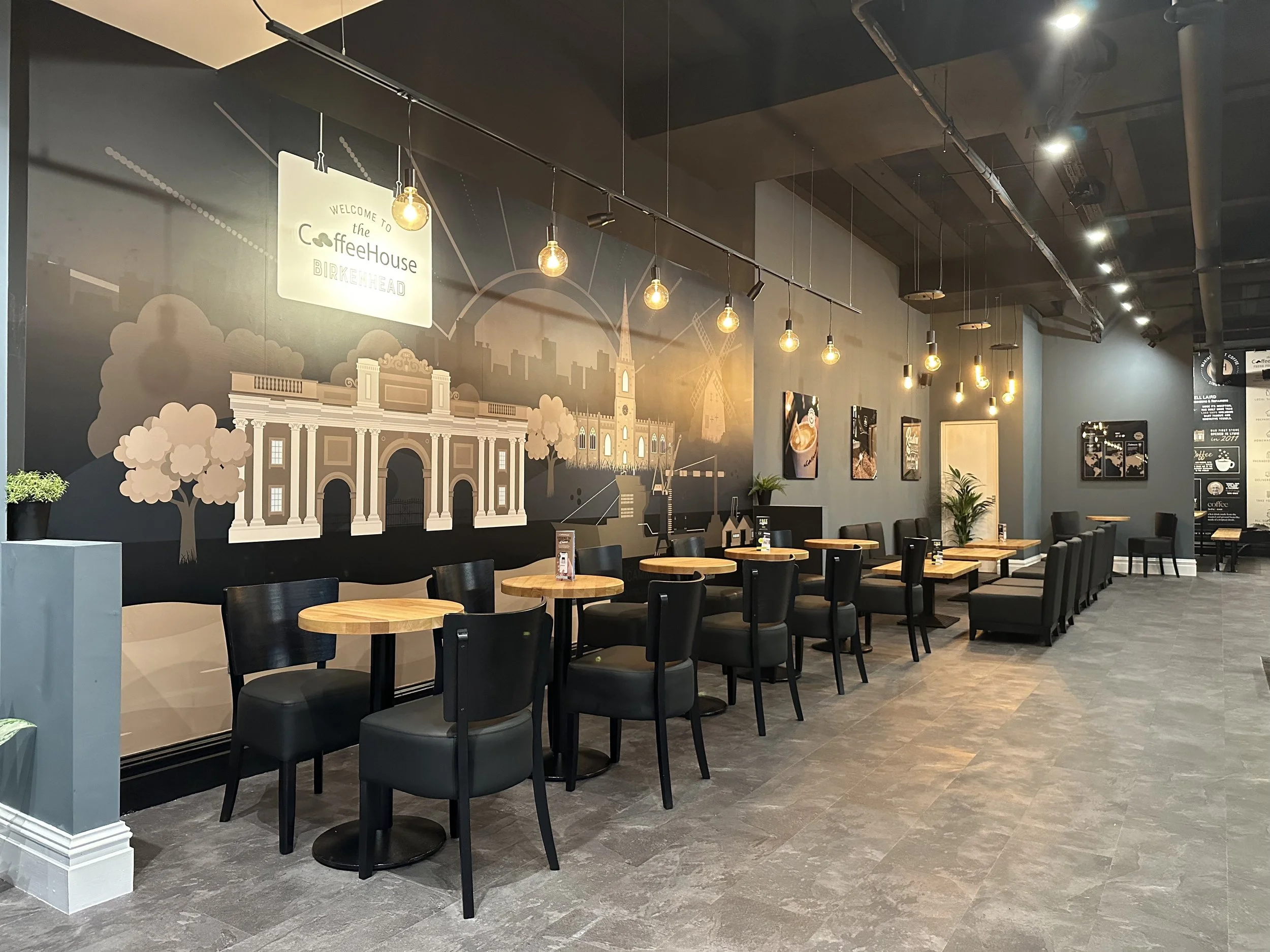 Modern cafe interior with wooden tables, black chairs, and wall mural.