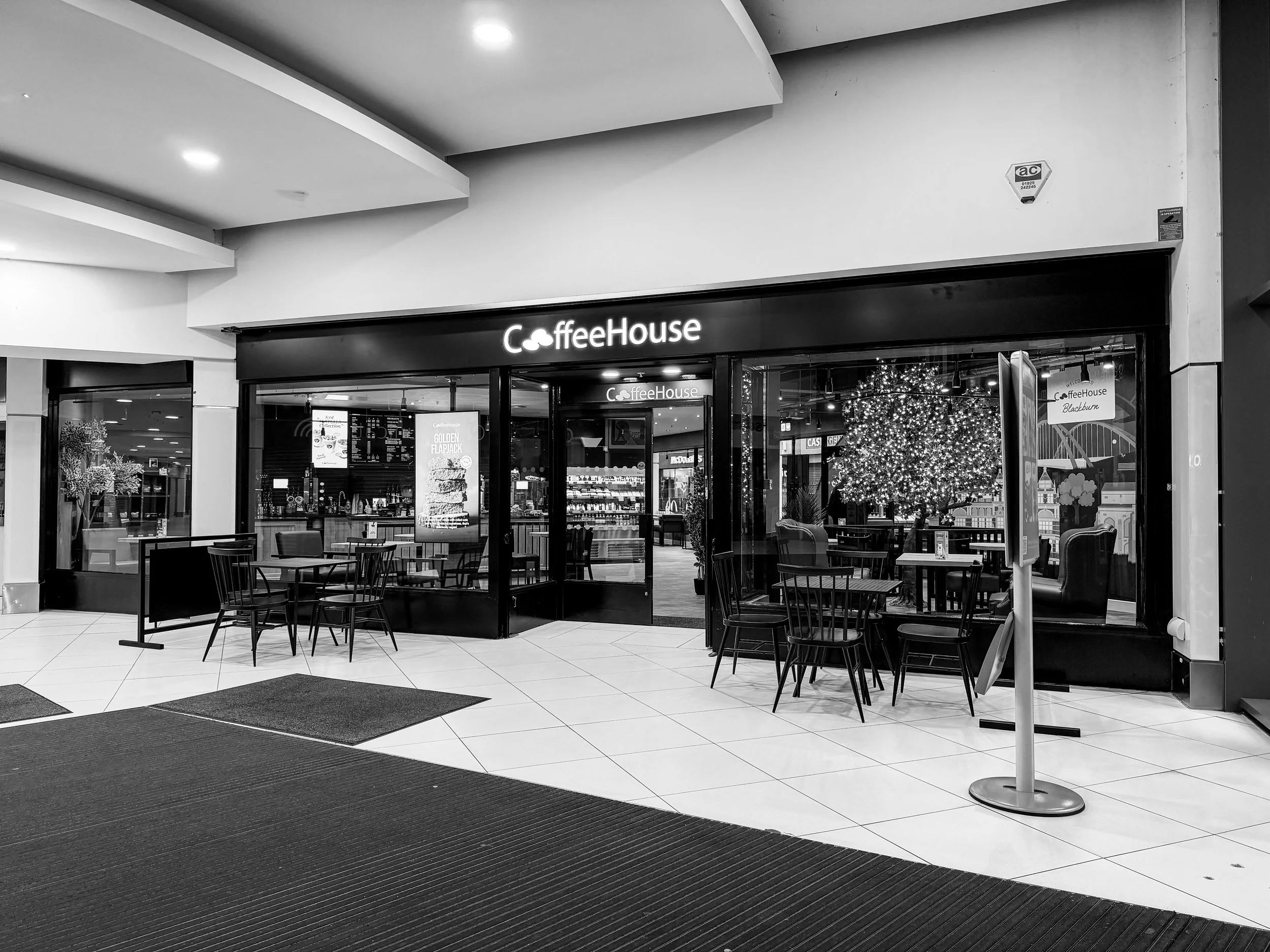 A sign with the words 'Opening Soon' over a background of interior lighting fixtures and wooden decor.