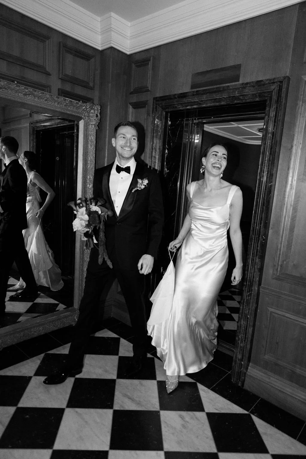 photo noire et blanche d'un couple marié sortant de l'ascenseur Londres