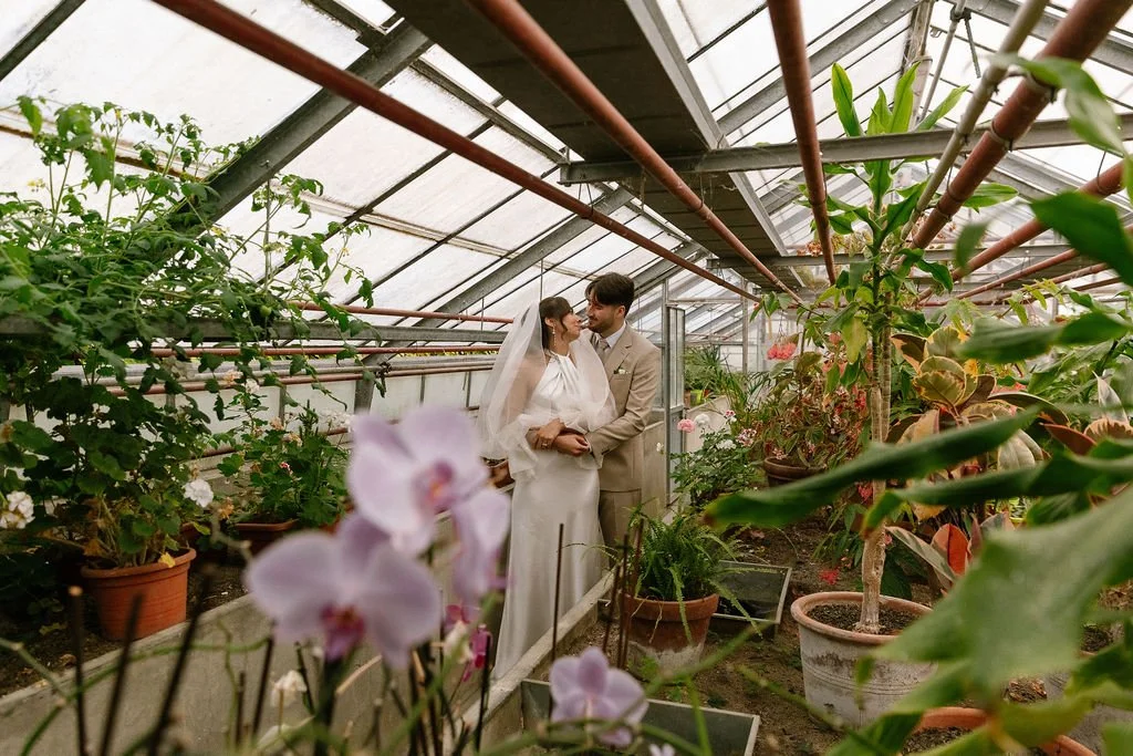 bride and groom holding each other in a greenhouse