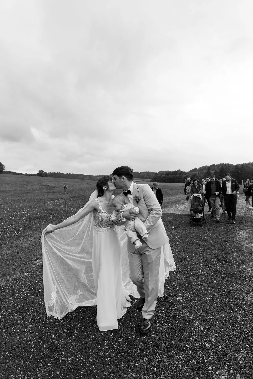 couple marié s'embrassant suivis de leur invités